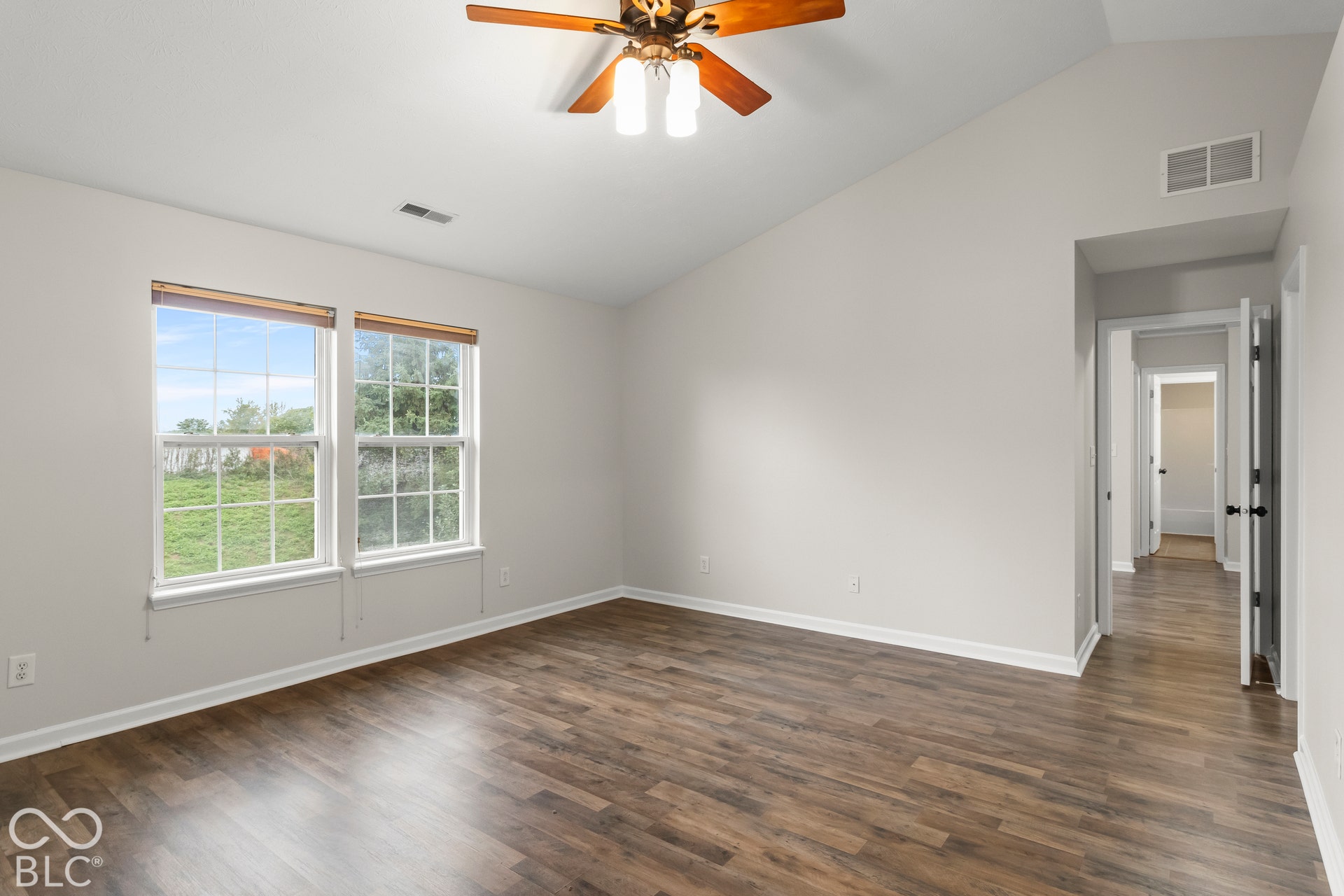 Vaulted ceiling, wood-finish flooring, dual windows, ceiling fan, and painted walls