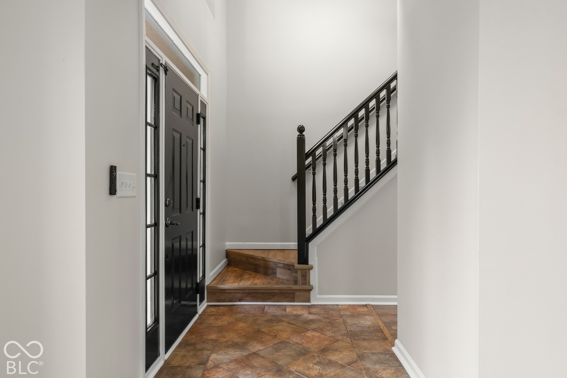 Entryway featuring a paneled front door with sidelights, a staircase with black balusters, and tile flooring