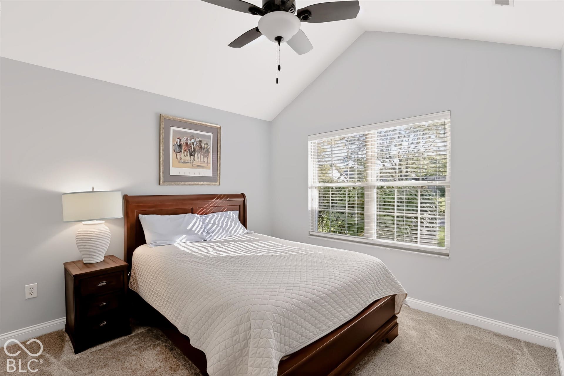 Vaulted ceiling, ceiling fan, carpet flooring, window with blinds, and light gray wall paint