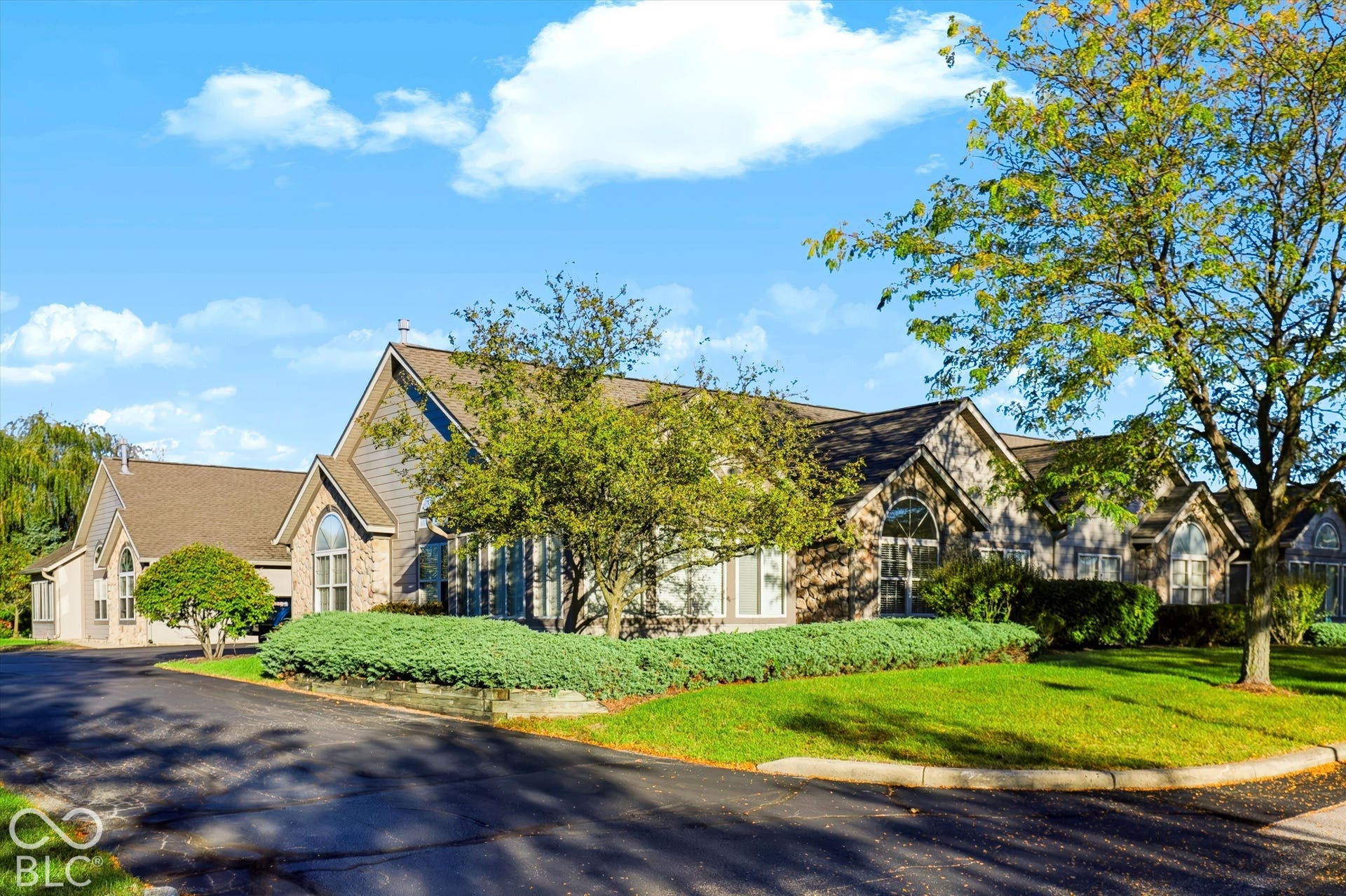 Multi-level exterior with gabled roof lines, stone and siding facade, arched windows, and extensive landscaping