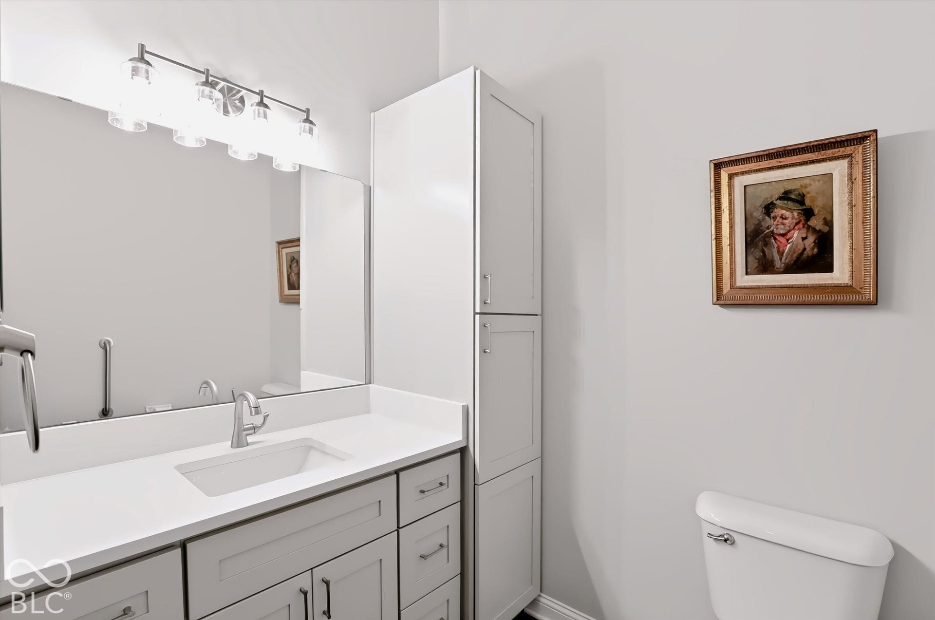 Vanity with light gray cabinetry, integrated rectangular sink, wall-mounted mirror, and brushed nickel faucet
