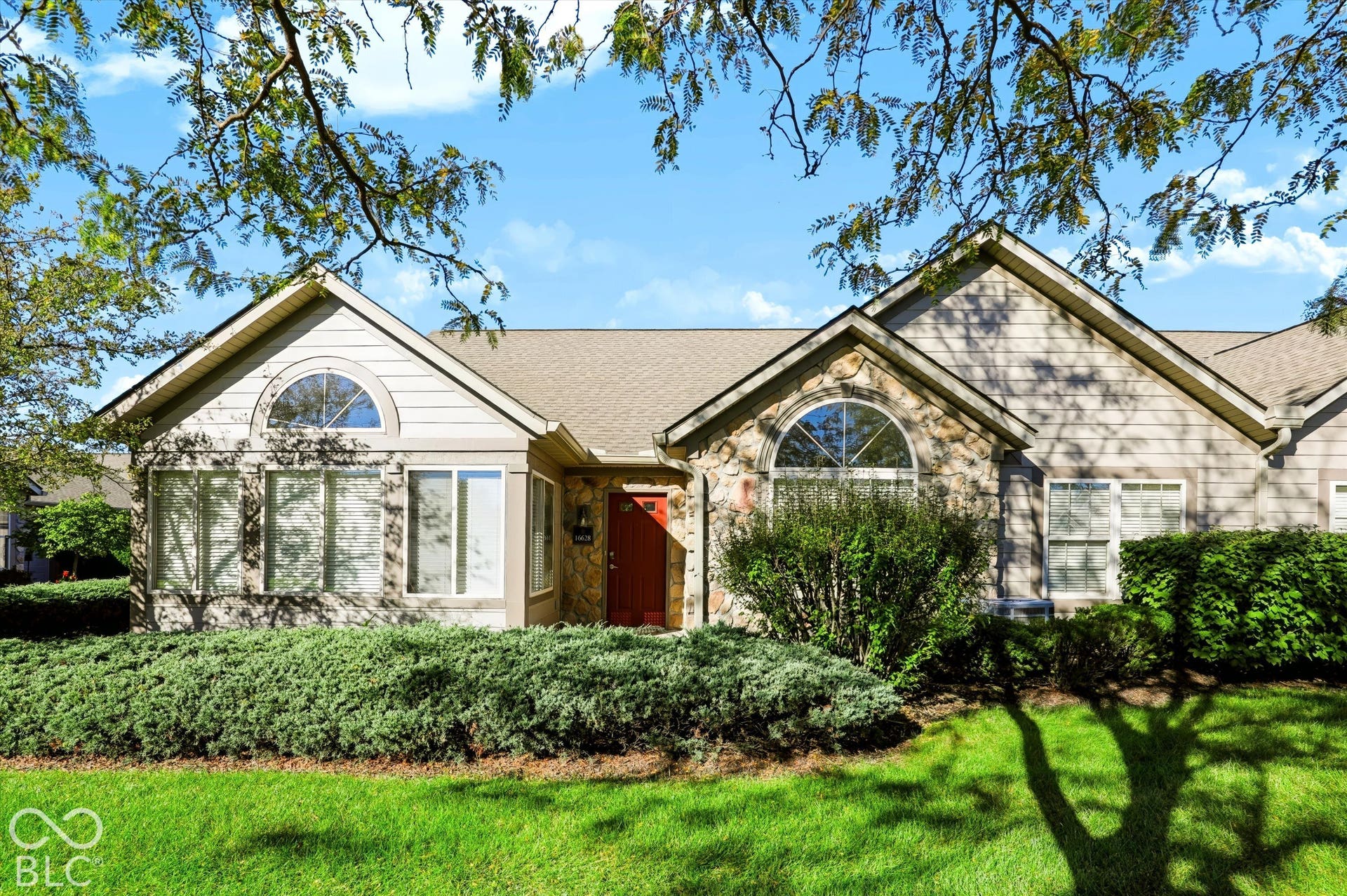Stone and siding exterior with gabled roofline, arched transom windows, and an accented entry door