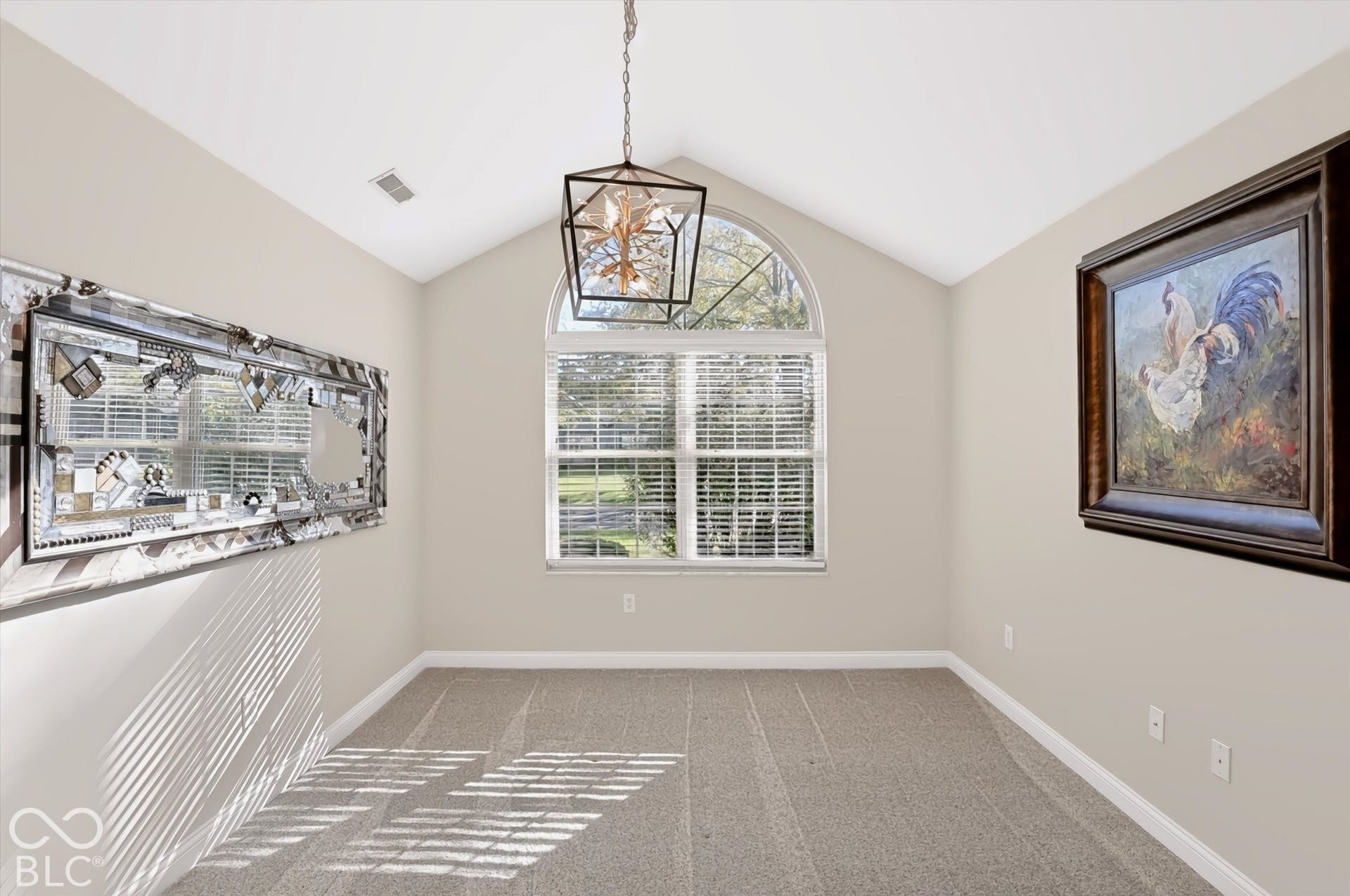 Vaulted ceiling with an arched transom window, contemporary chandelier, and carpeting