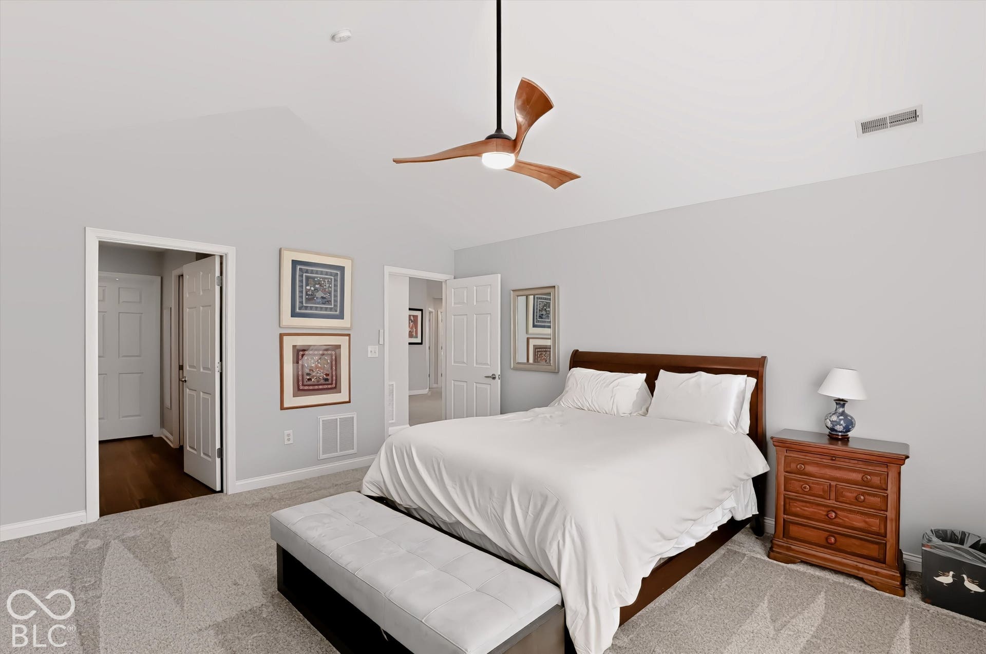 Vaulted ceiling with a wood-finish ceiling fan, neutral wall paint, light-colored carpet, and white trim