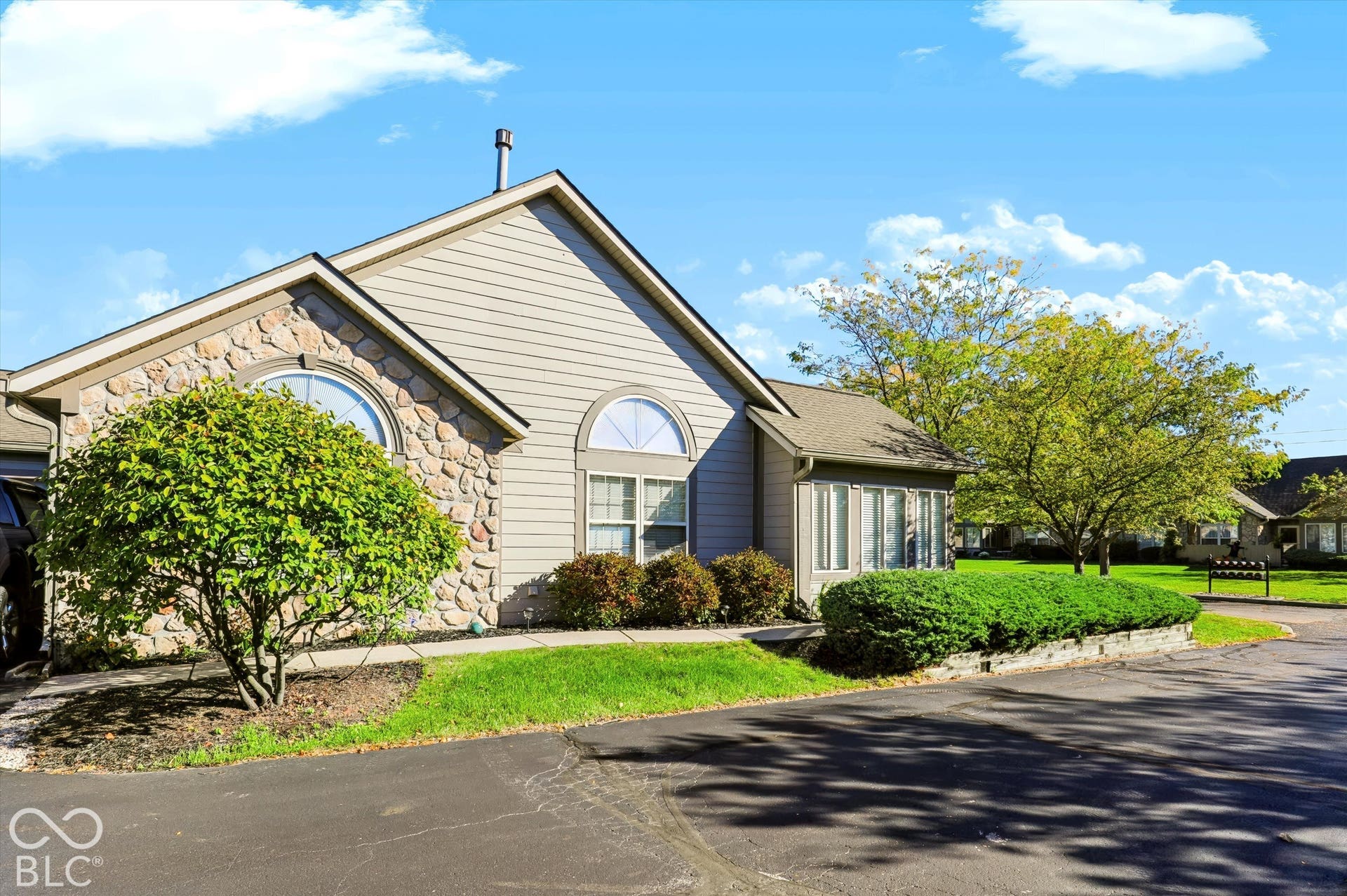 Exterior with stone veneer accents, arched windows, and a gabled roof