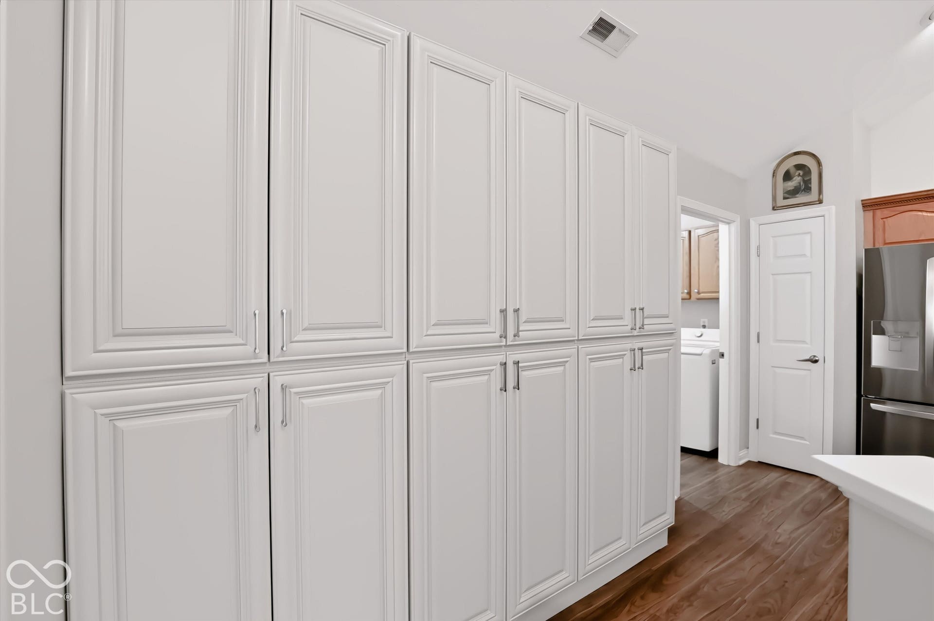 Extensive white paneled cabinetry with silver-tone hardware and wood-finish flooring