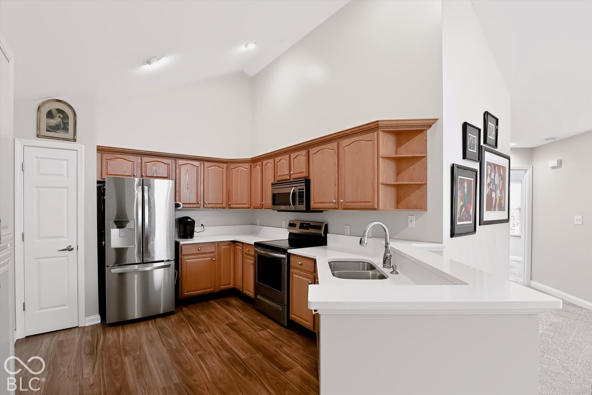 Kitchen featuring wood-finish flooring, vaulted ceiling, recessed lighting, wood cabinetry, and stainless steel appliances