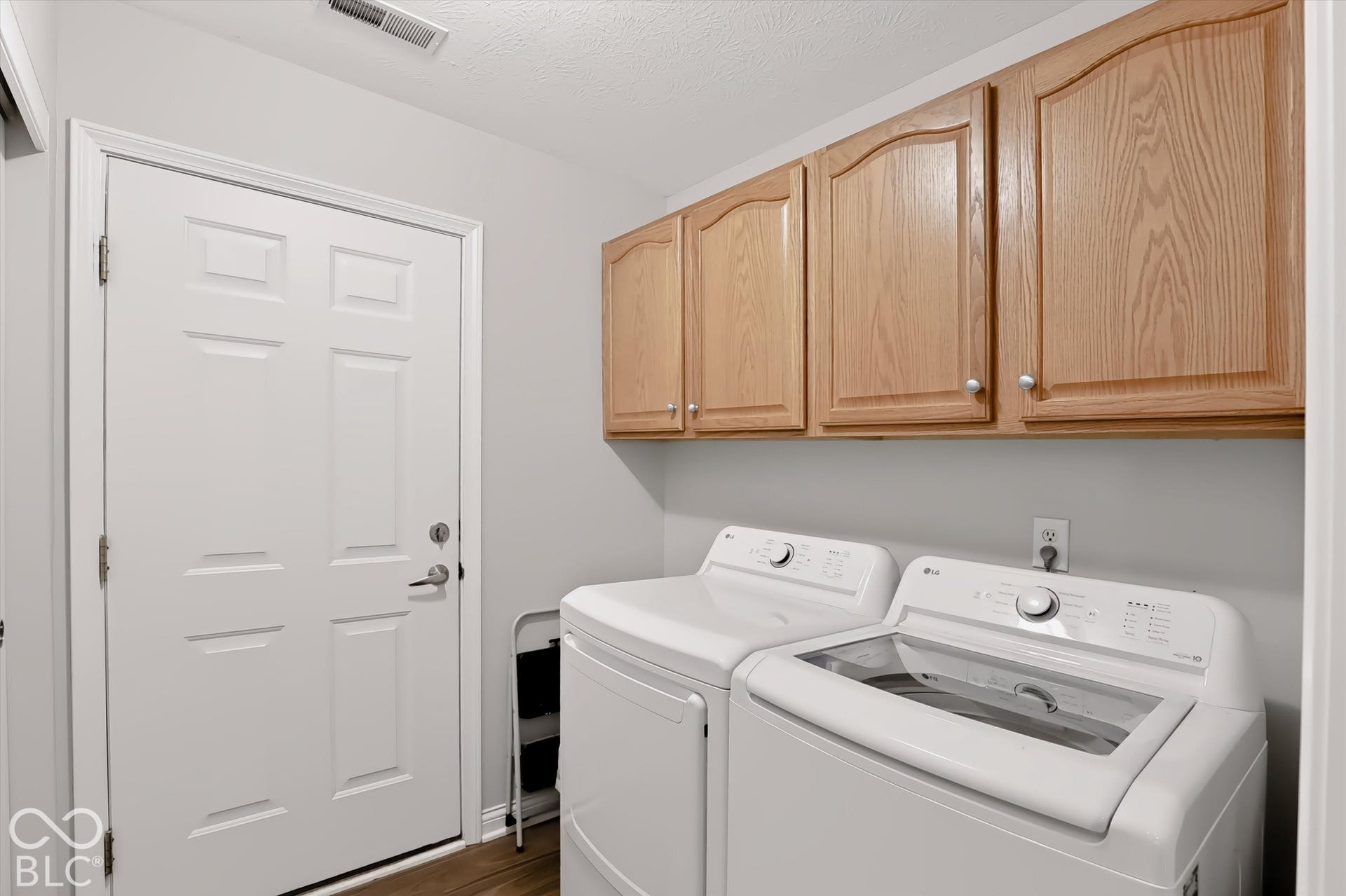 Laundry area with wood-finish cabinetry, light gray walls, and wood-finish flooring