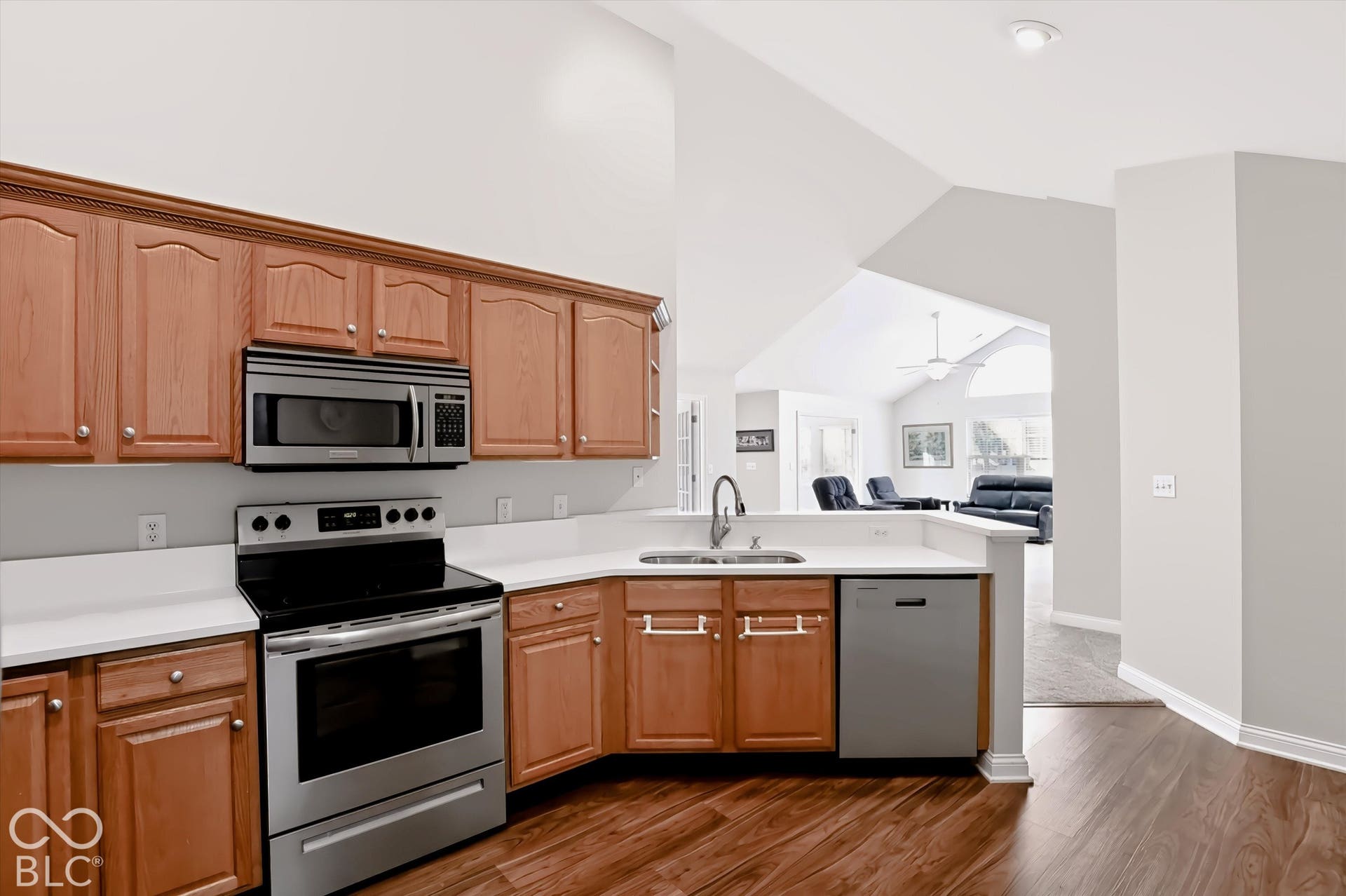 Kitchen featuring wood-finish flooring, light wood cabinetry, white countertops, and stainless steel appliances including a range, microwave, and dishwasher