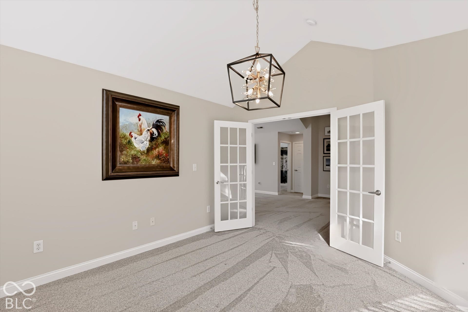 Vaulted ceiling with a geometric chandelier, neutral wall paint, and double French doors