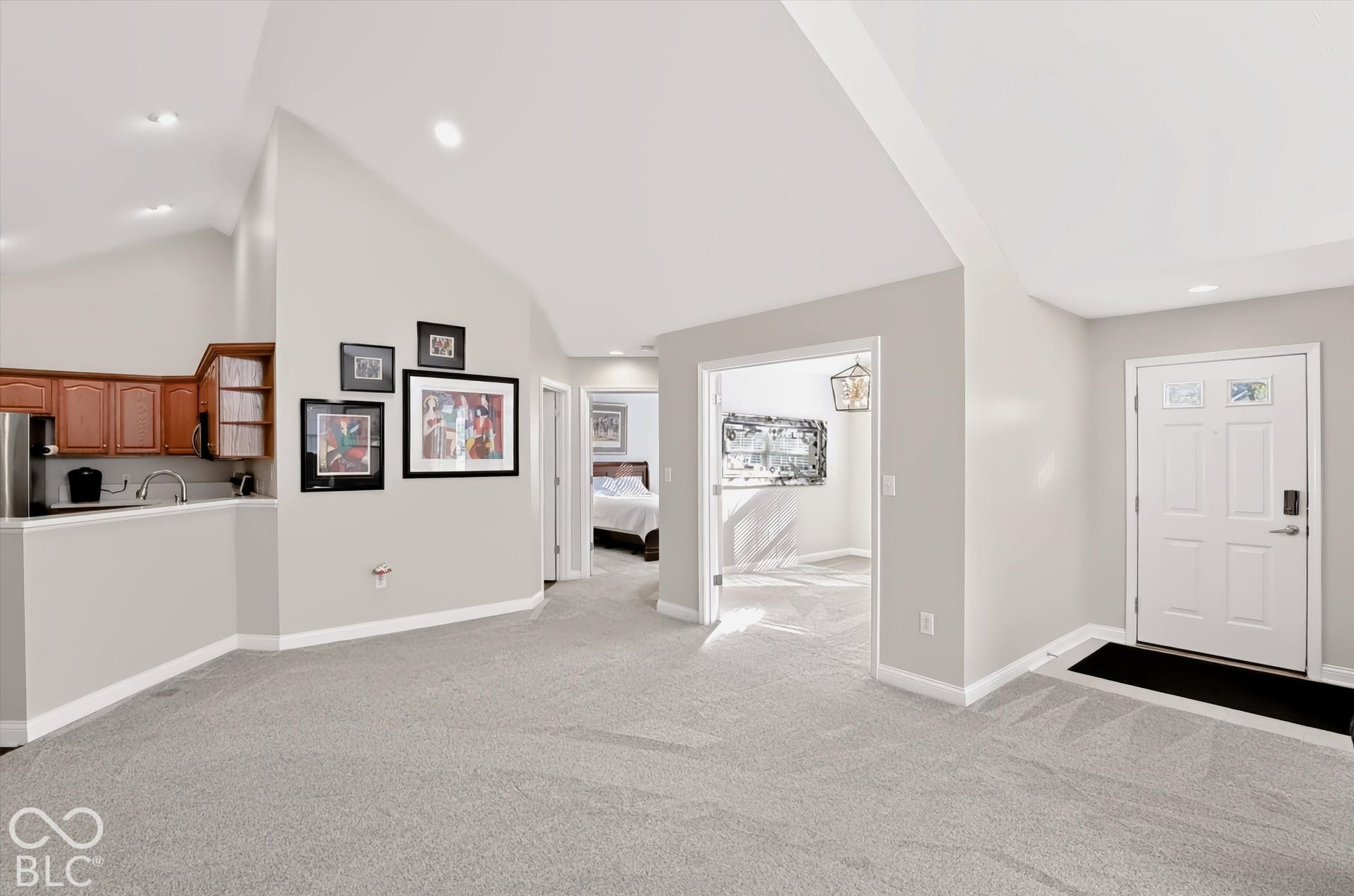 Vaulted ceiling, recessed lighting, wood cabinetry, built-in sink, and a panel door with decorative glass inserts