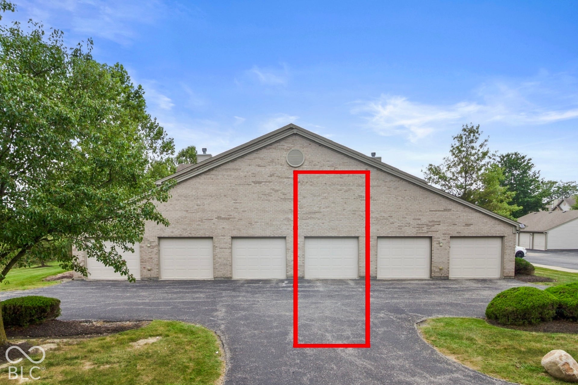 Brick exterior with a gabled roofline, multiple garage bays, and an asphalt driveway