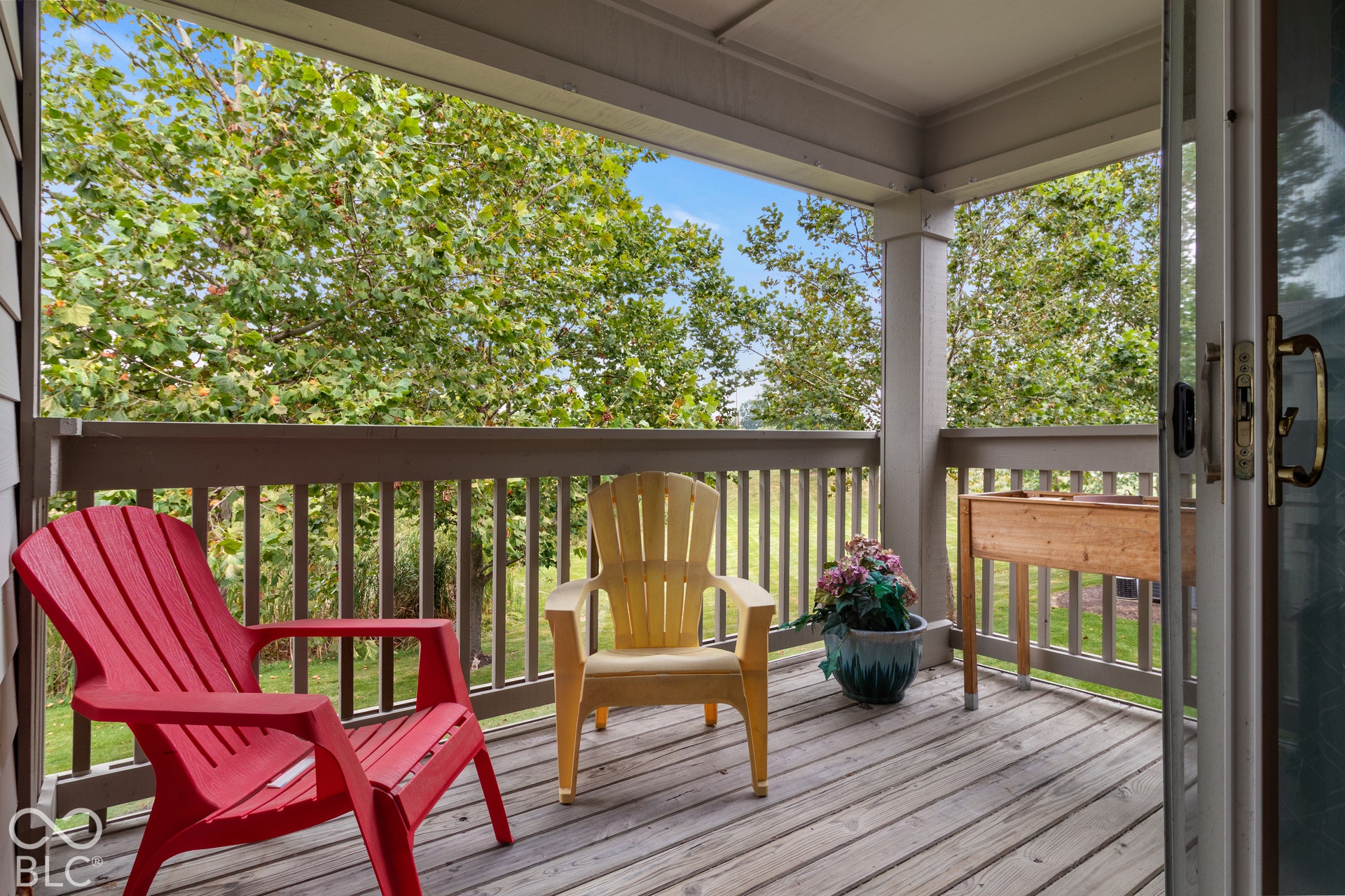 Covered outdoor deck with wood-finish flooring, wood railing, and a sliding glass door entry