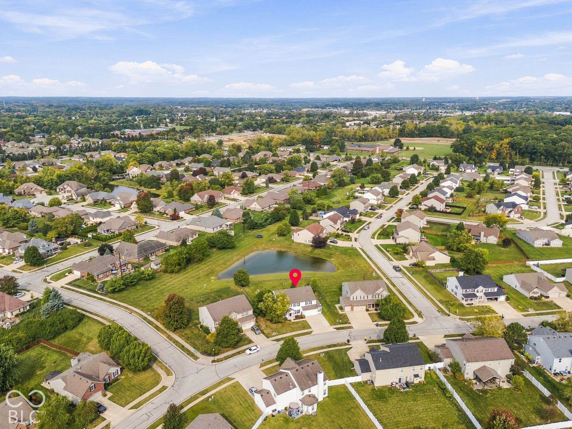 Residential property featuring a tranquil pond, surrounded by landscaped lawns and mature trees