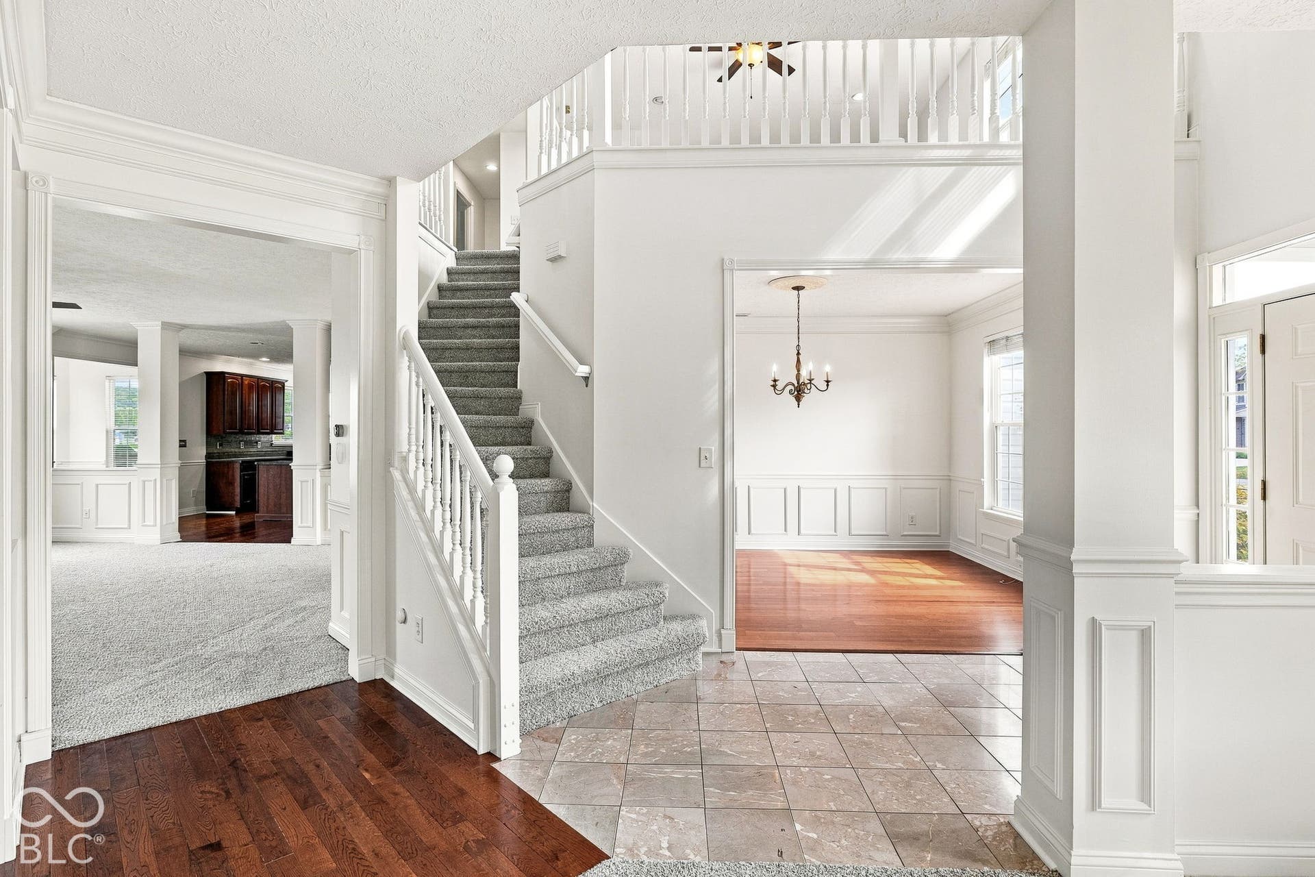 Two-story entry foyer with a carpeted staircase, balustrade, and upper-level railing
