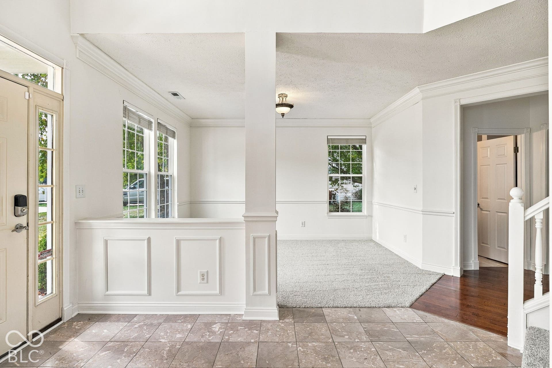 Entry foyer with tile flooring and a decorative half-wall, featuring wainscoting and crown molding