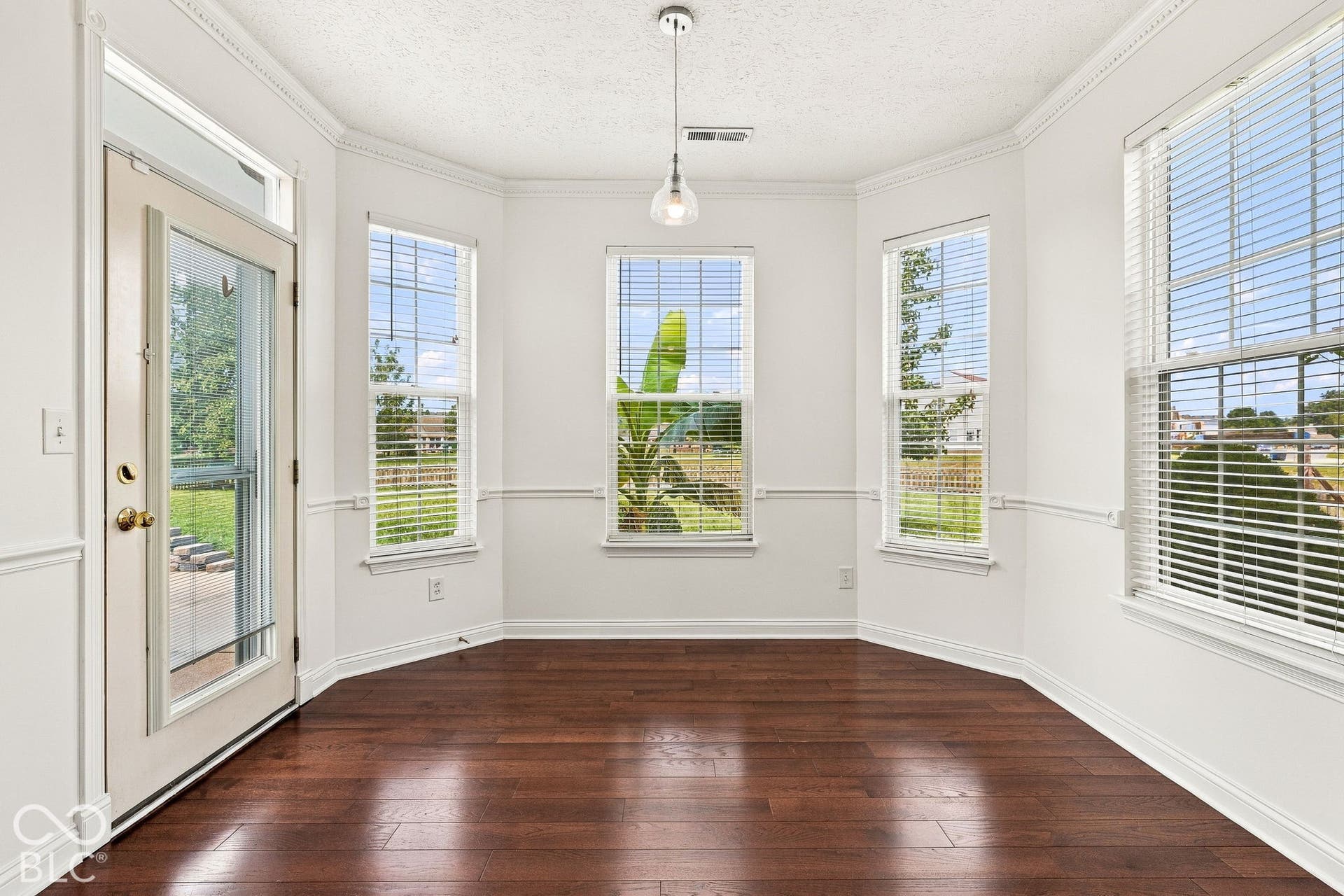 Bay window dining space with rich wood-finish flooring, multiple windows, and a glass-paneled exterior door