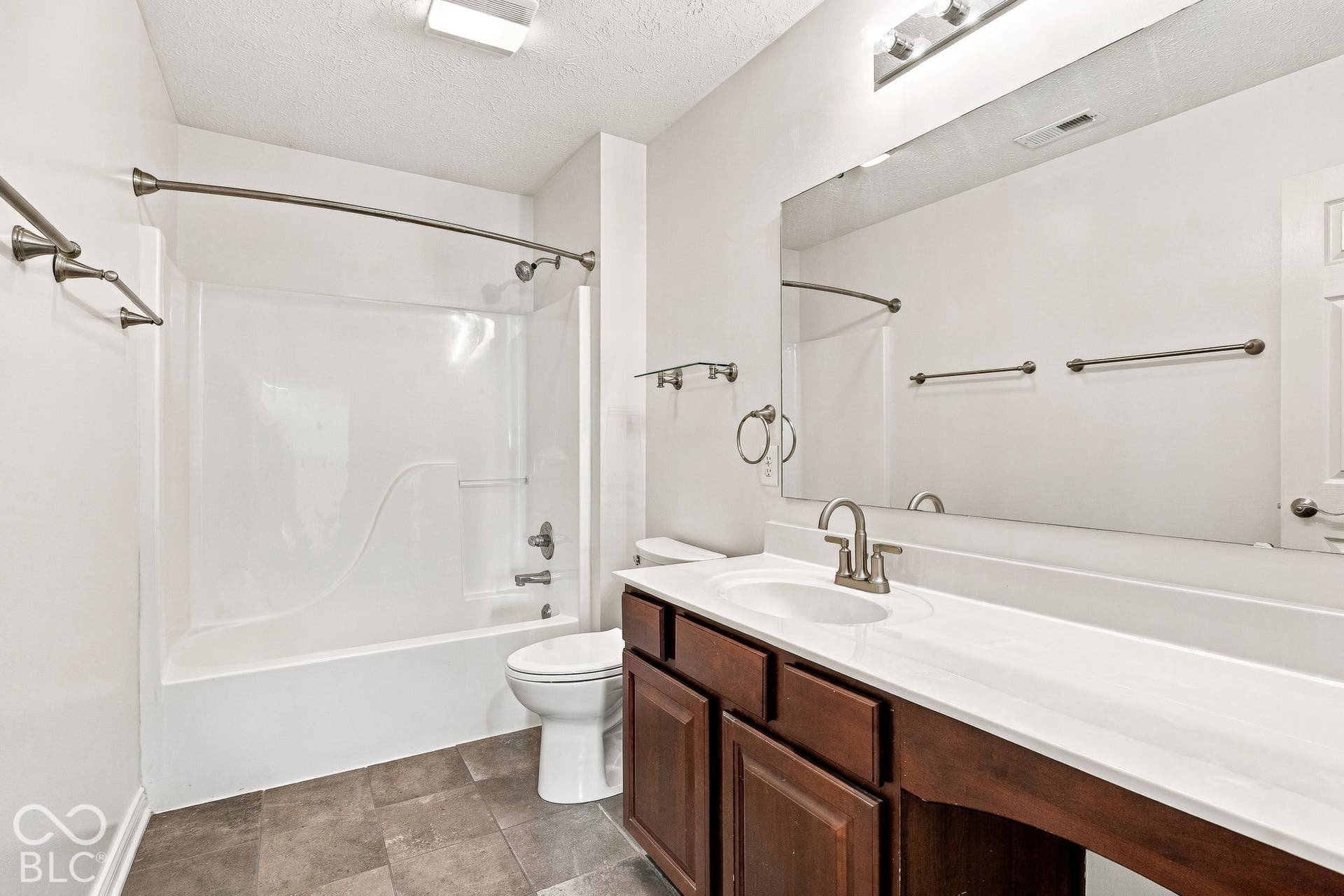 White vanity countertop with an integrated sink and brushed nickel faucet, large wall-mounted mirror, and dark wood-finish cabinetry