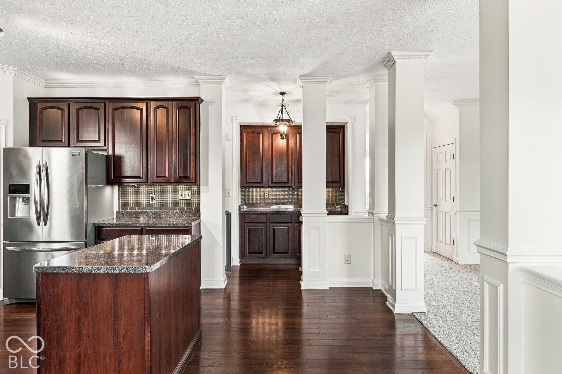 Kitchen featuring dark wood cabinetry, stainless steel refrigerator, granite countertops, and a tile backsplash