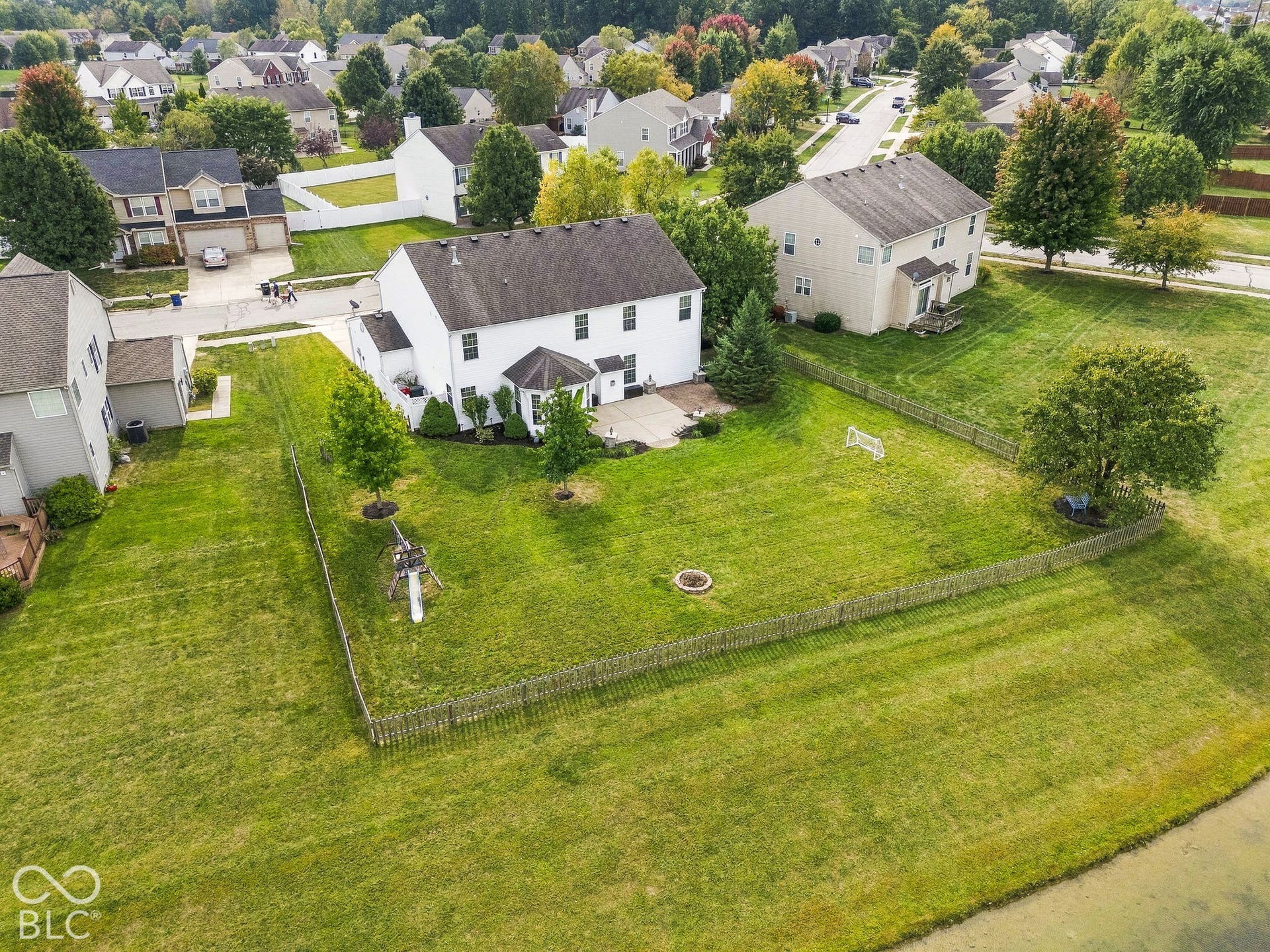 Expansive backyard featuring a manicured lawn, mature trees, and a partial privacy fence