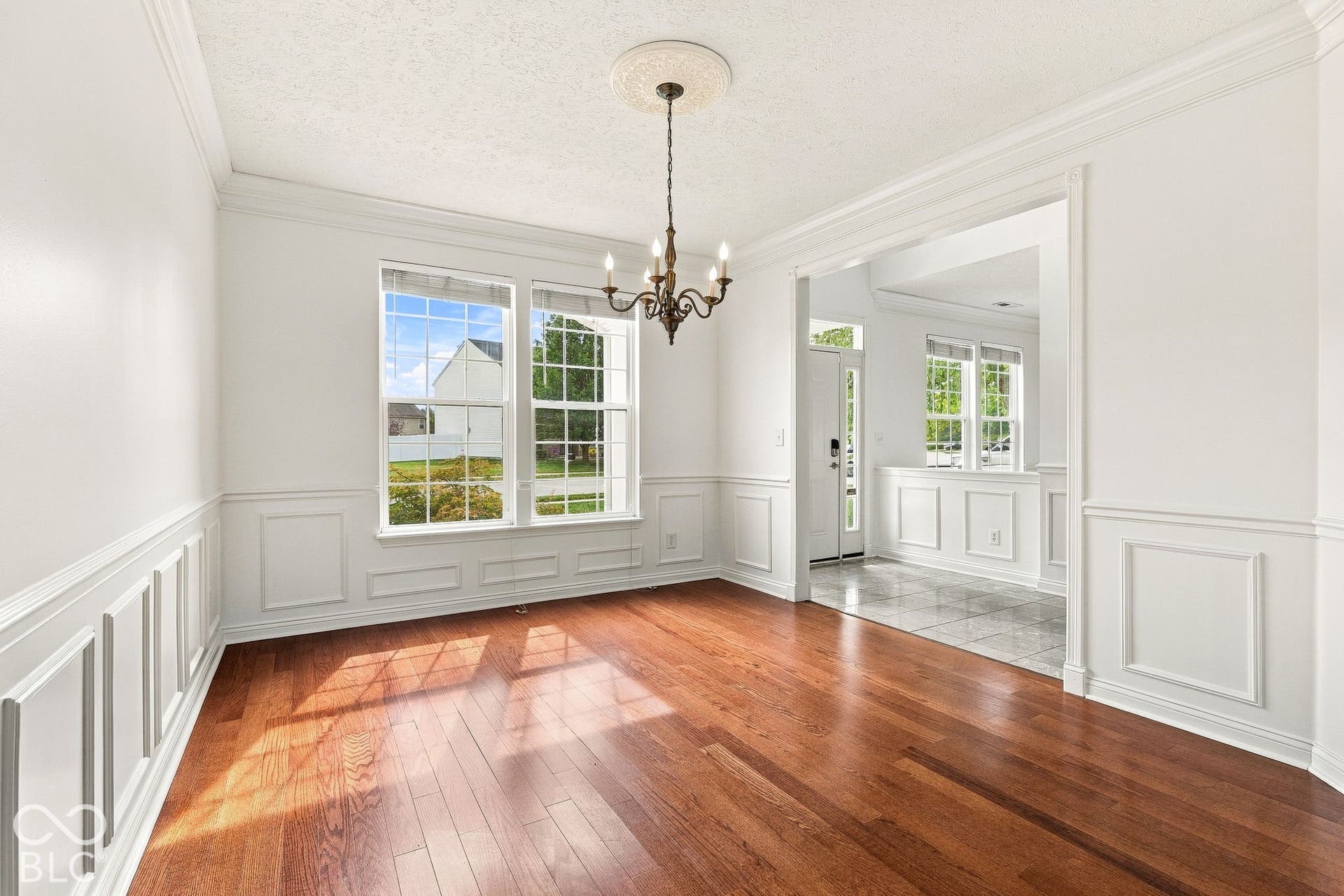 Hardwood-finish flooring, wainscoting, crown molding, double windows, and a chandelier with a ceiling medallion