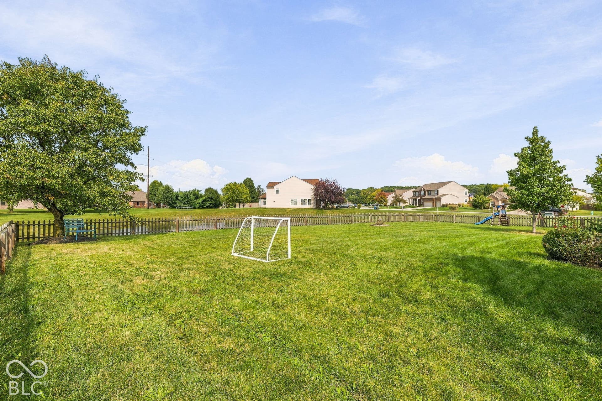 Expansive grassy yard area with a picket fence perimeter
