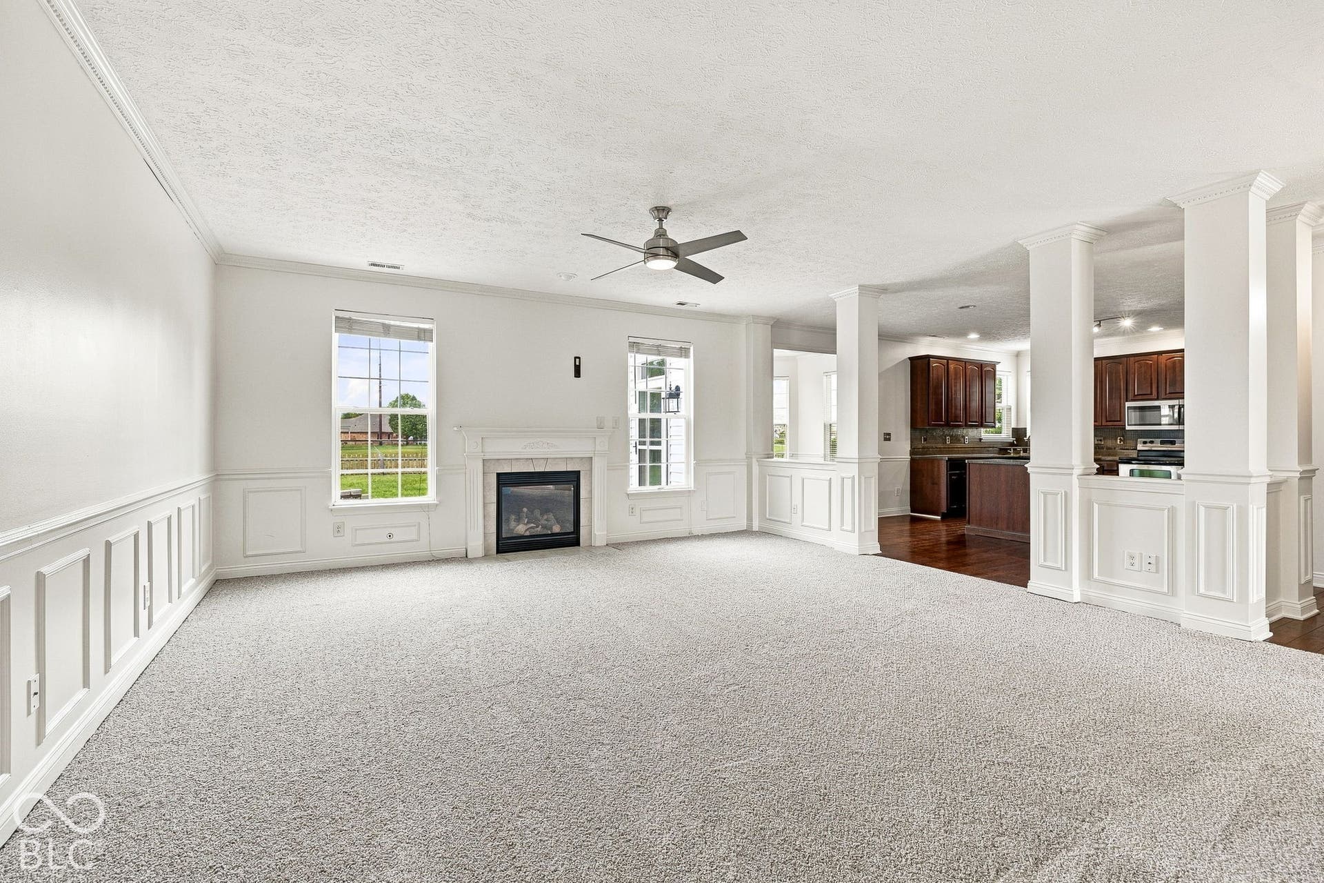 Spacious living area featuring light-toned carpeting and wainscoting