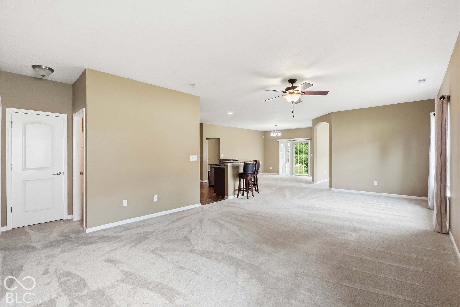 Spacious great room with light color carpeting and neutral wall tones