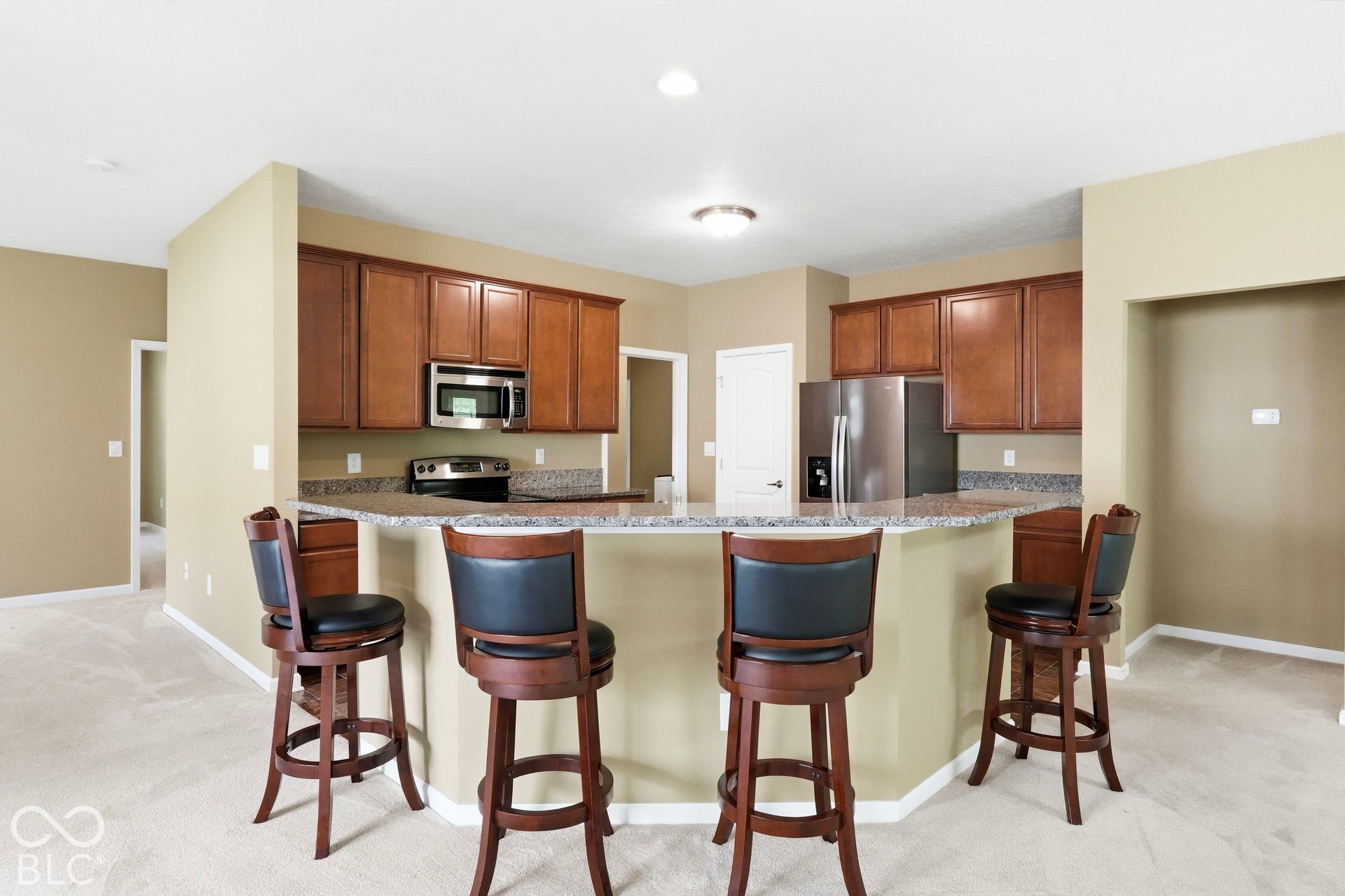 Kitchen with wood-finish cabinetry, stainless steel appliances, and a granite-style countertop breakfast bar
