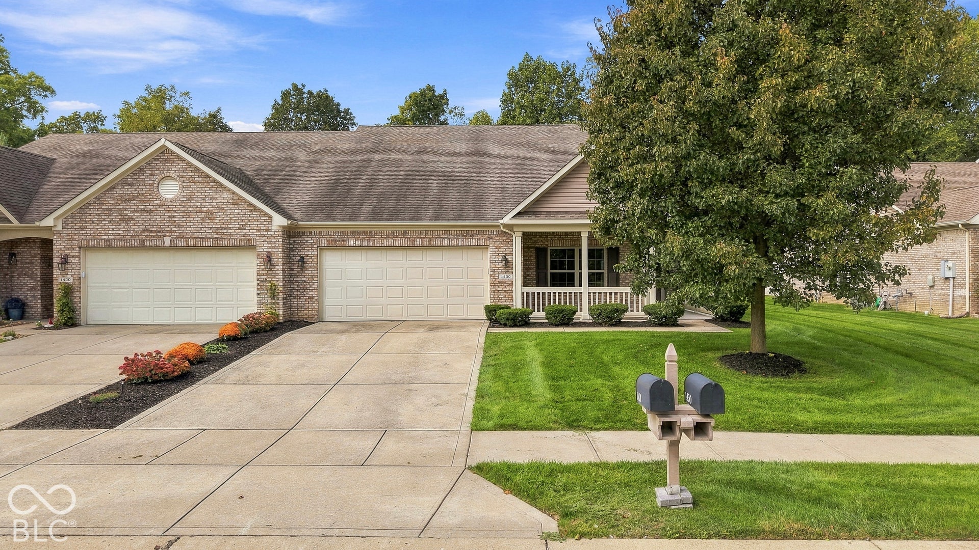 Brick exterior with a covered front porch, concrete driveway, and attached two-car garage