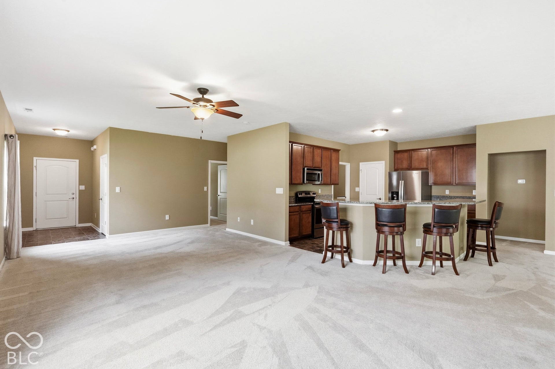 Spacious living area with ceiling fan light fixture, recessed lighting, and soft carpeting