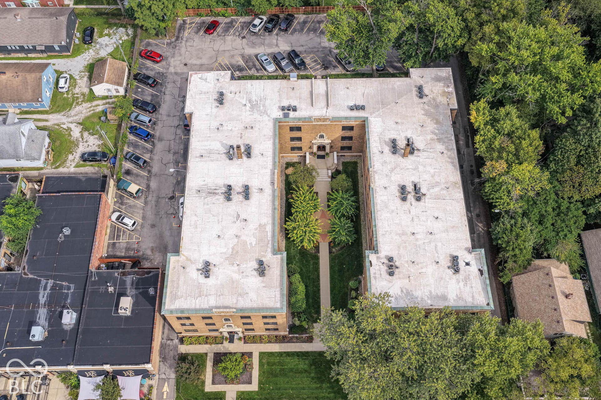 U-shaped building with a central courtyard, a dedicated parking area, and surrounding mature trees