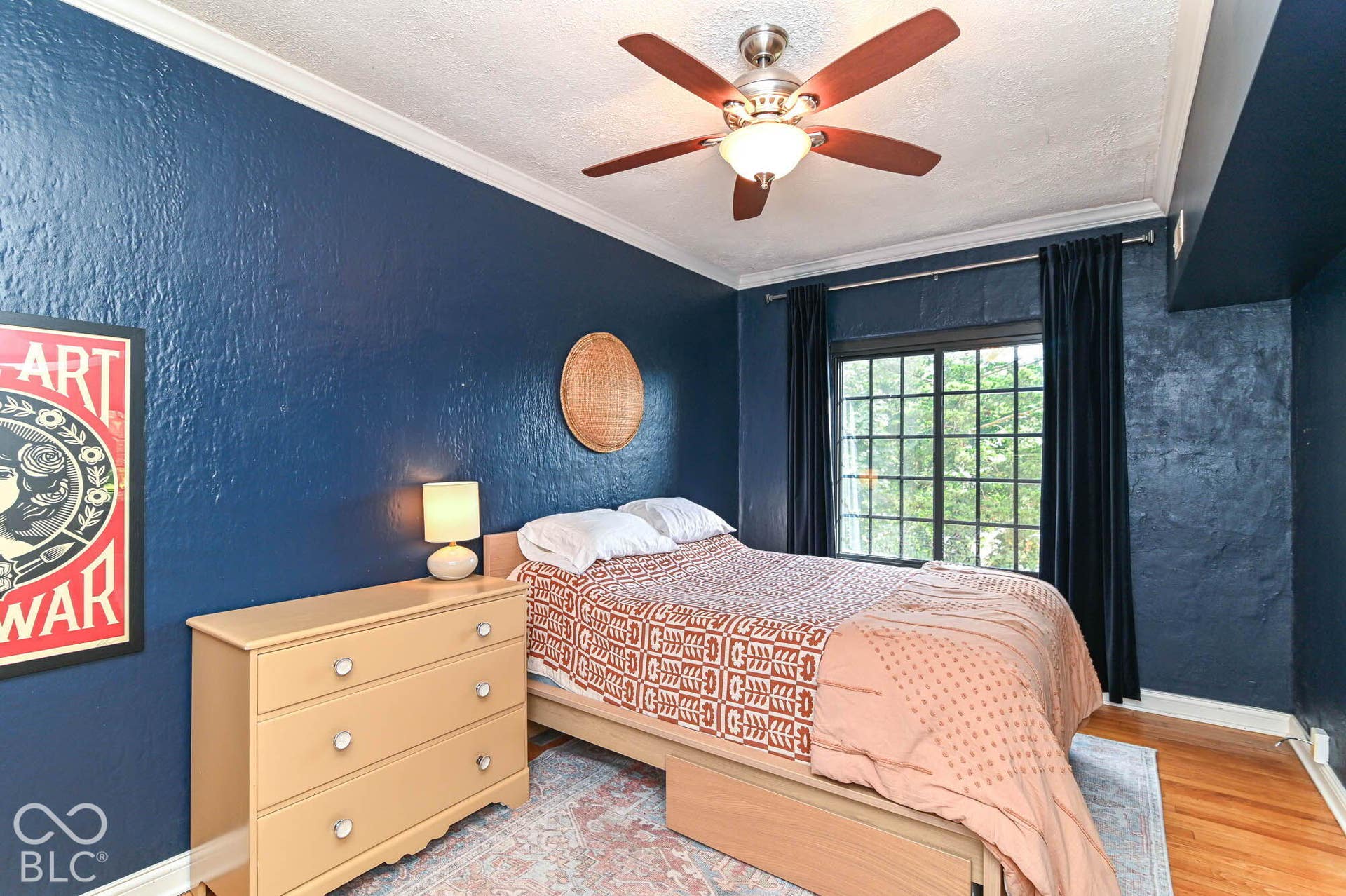 Hardwood flooring, crown molding, a ceiling fan with integrated lighting, and a large window with privacy curtains