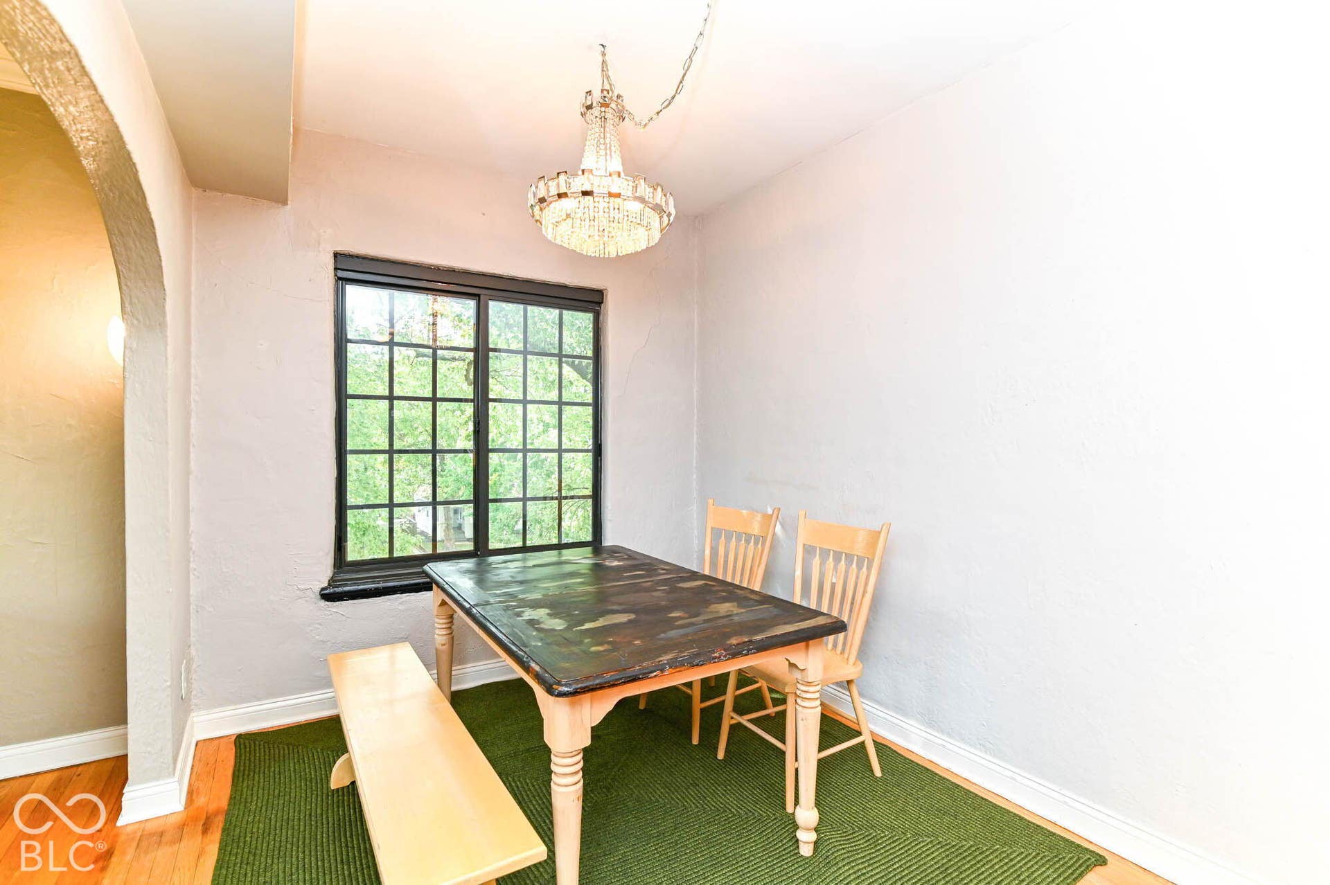 Archway entry, hardwood-finish flooring, chandelier lighting, and a large grid-pattern window