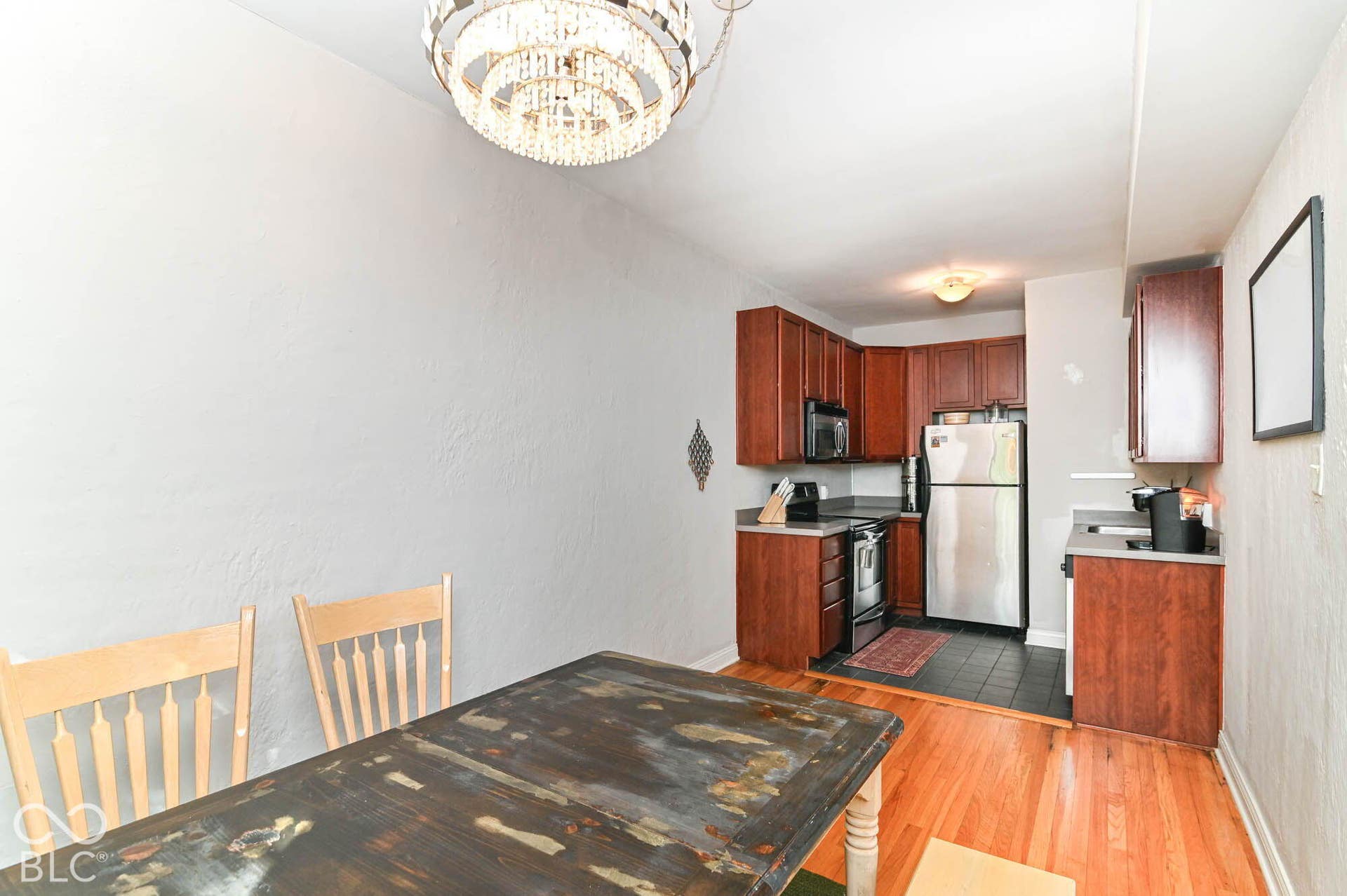 Kitchen featuring wood-finish cabinetry, stainless steel appliances, dark countertops, and tile flooring