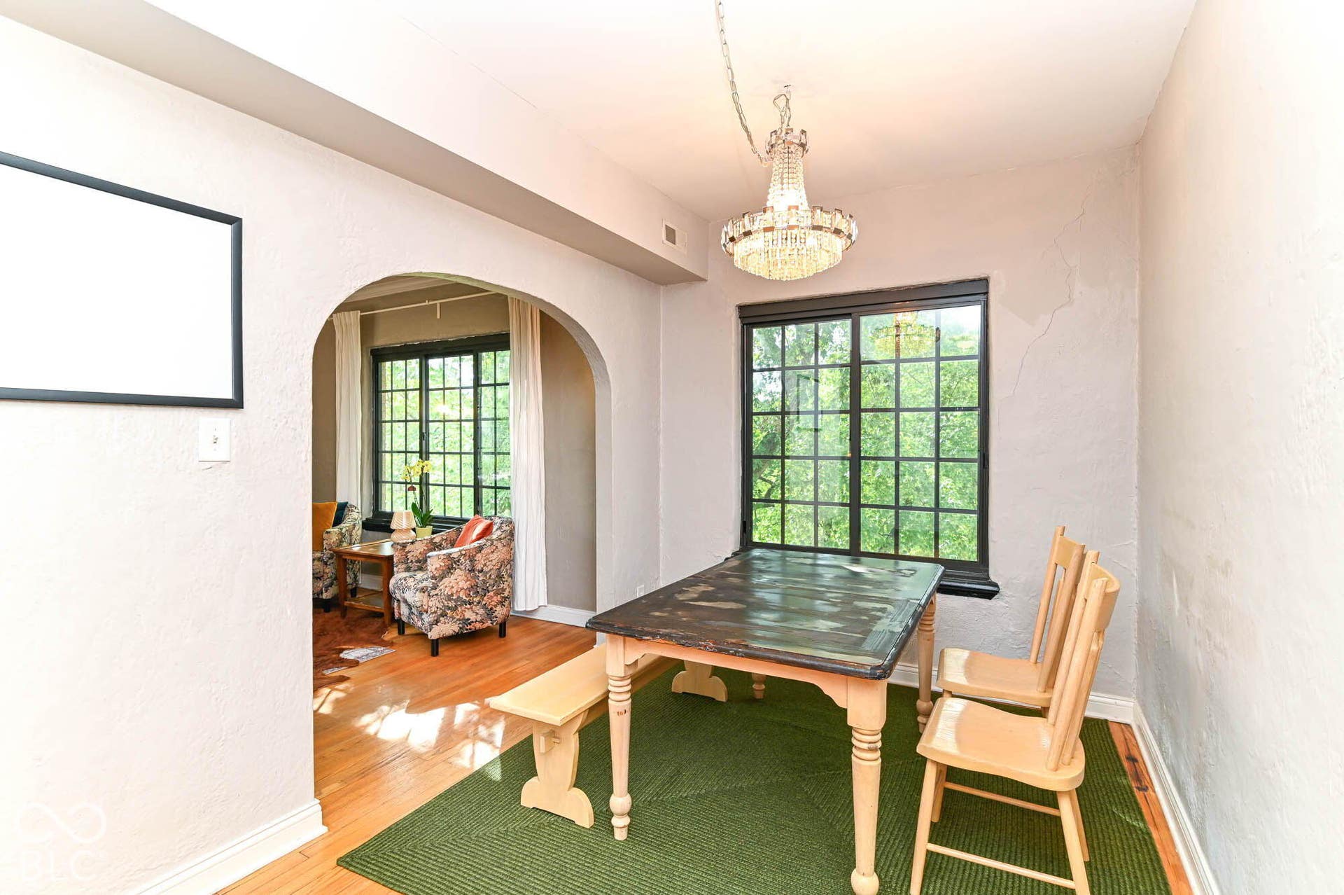 Hardwood flooring, arched doorway, paneled window, built-in lighting fixture, and textured walls