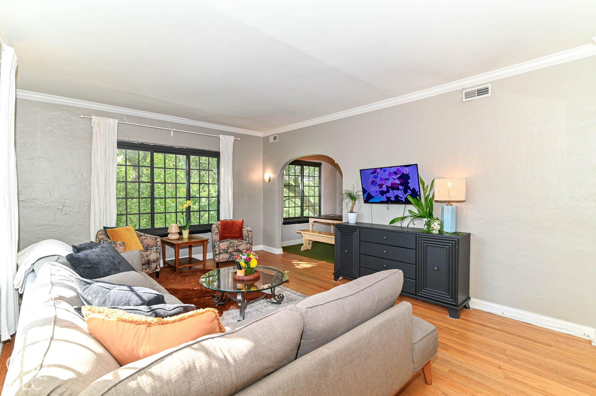 Hardwood flooring, crown molding, arched entryway, and multi-pane windows