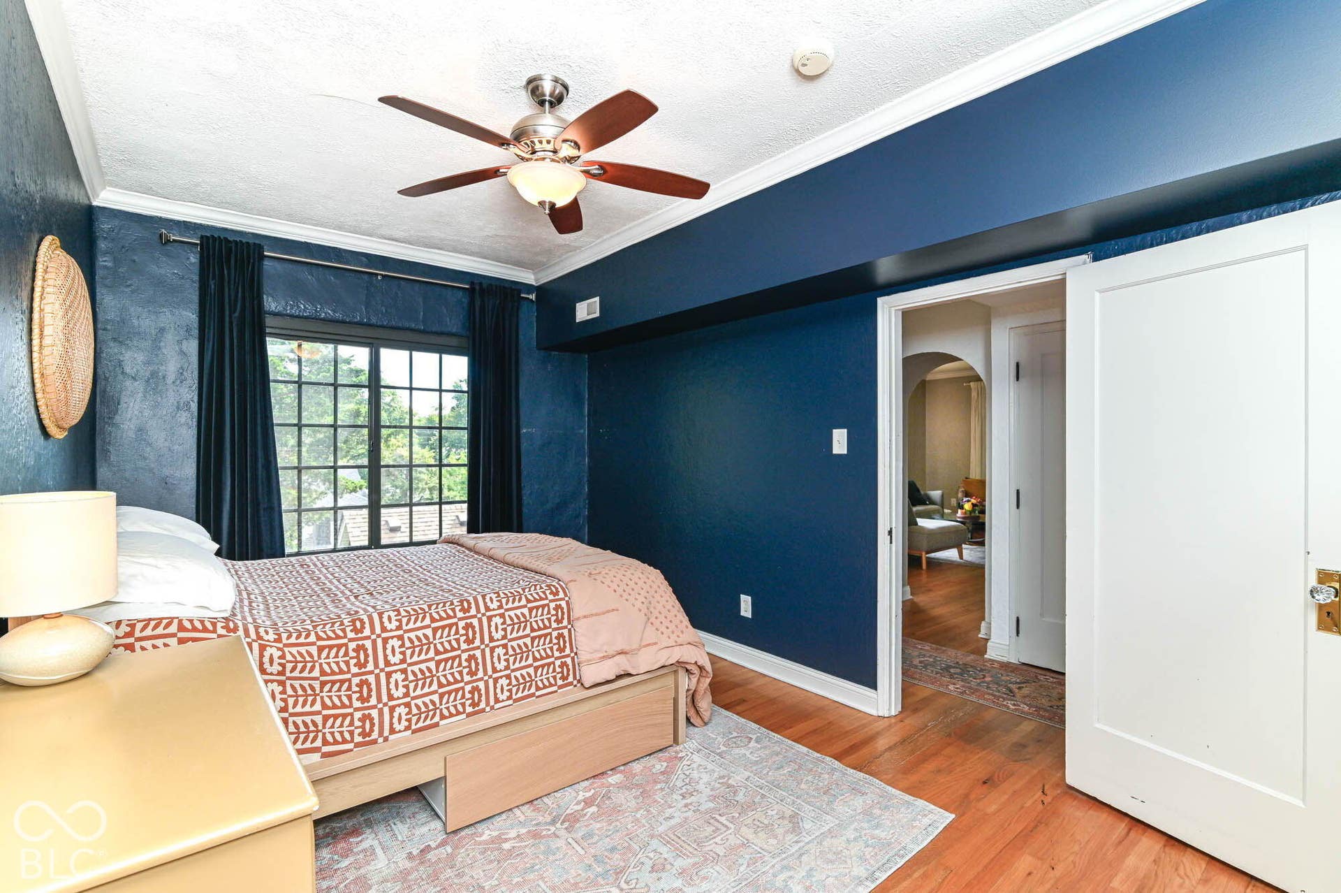 Hardwood flooring, painted walls, crown molding, a ceiling fan with integrated lighting, and a white interior door