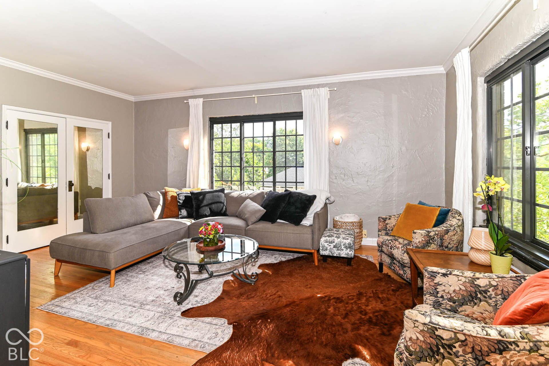 Hardwood flooring, crown molding, wall sconces, French doors, and large grid-pattern windows