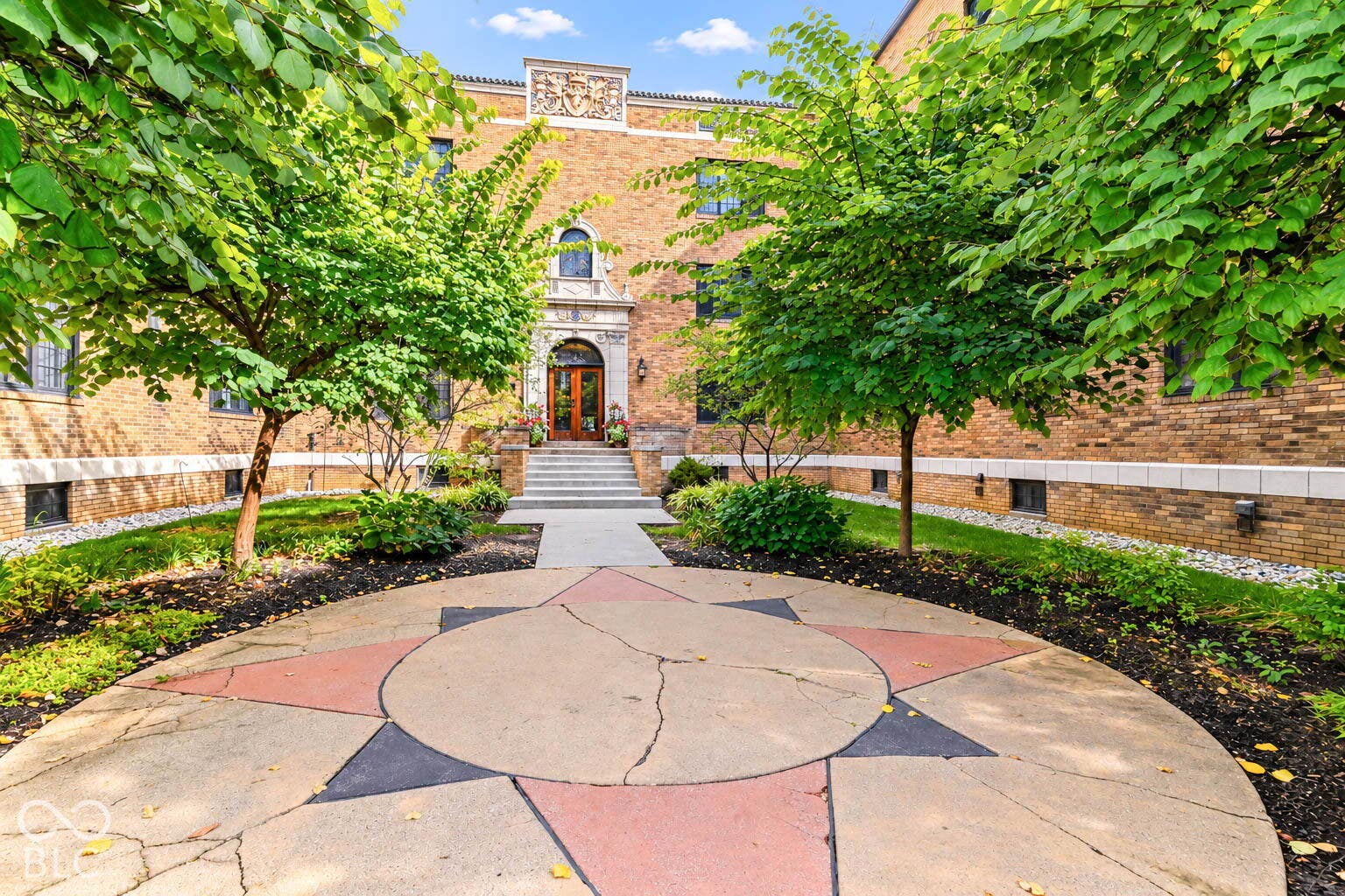 Brick exterior with decorative stone accents, arched entryway, and mature landscaping