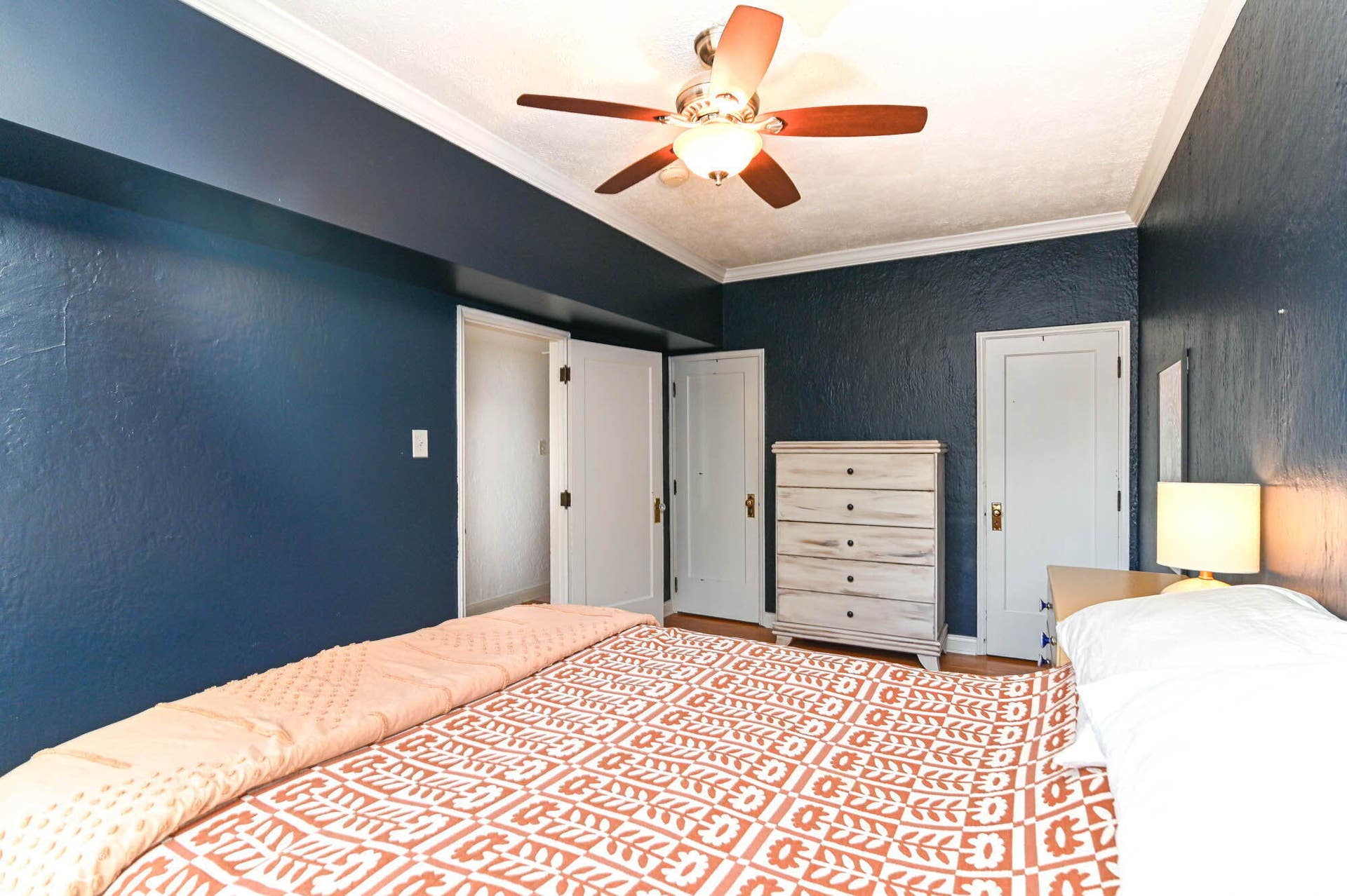 Ceiling fan with integrated lighting, crown molding, two panel doors, and textured wall finish