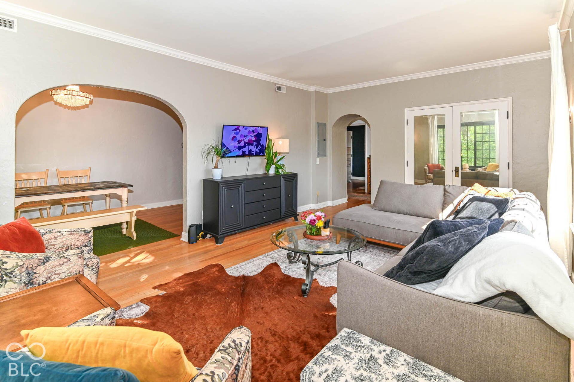 Hardwood-style flooring throughout, arched doorways, white trim and crown molding, and double glass-paneled doors
