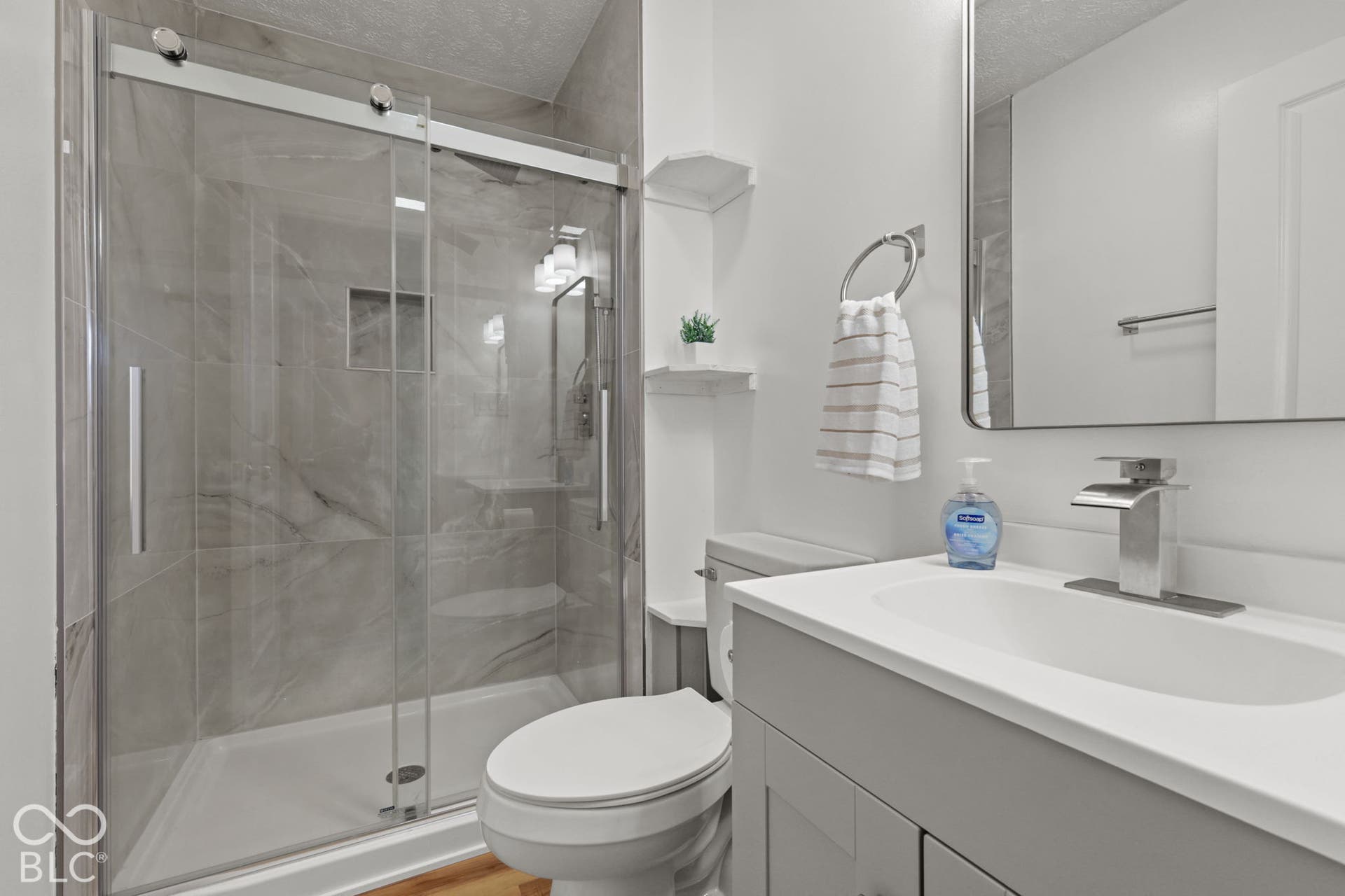Walk-in shower with sliding glass doors, a built-in shower niche, and full-height tile surround