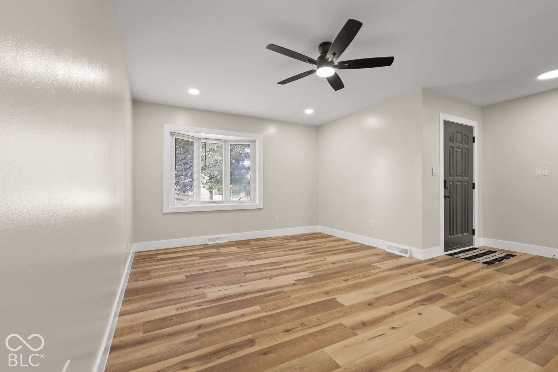 Wood-finish flooring, bay window, recessed lighting, and a ceiling fan with integrated lighting