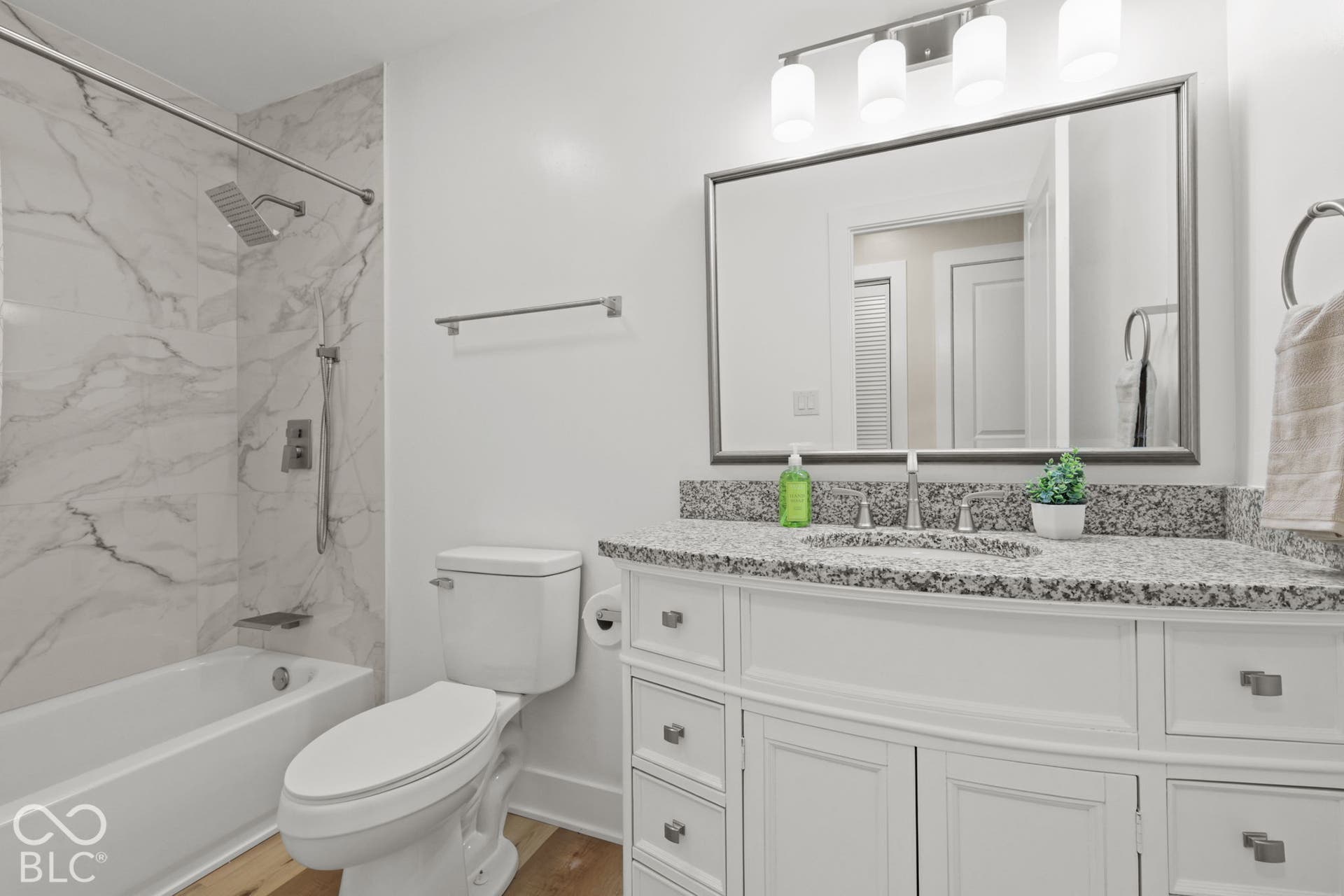 White vanity with a granite countertop, undermount sink, and brushed nickel fixtures