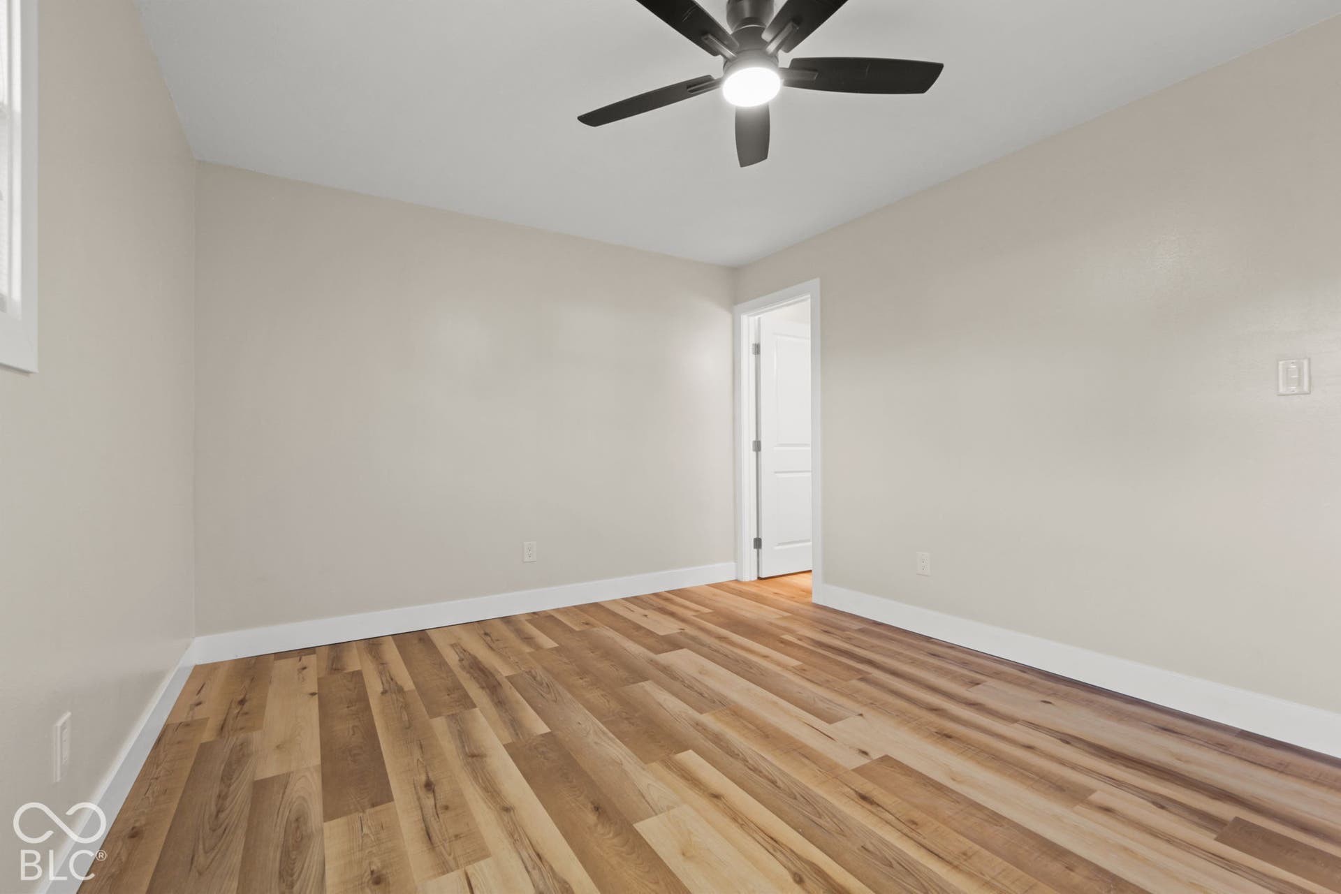 Hard-surface flooring, ceiling fan with integrated lighting, neutral wall paint, white trim, and white interior door