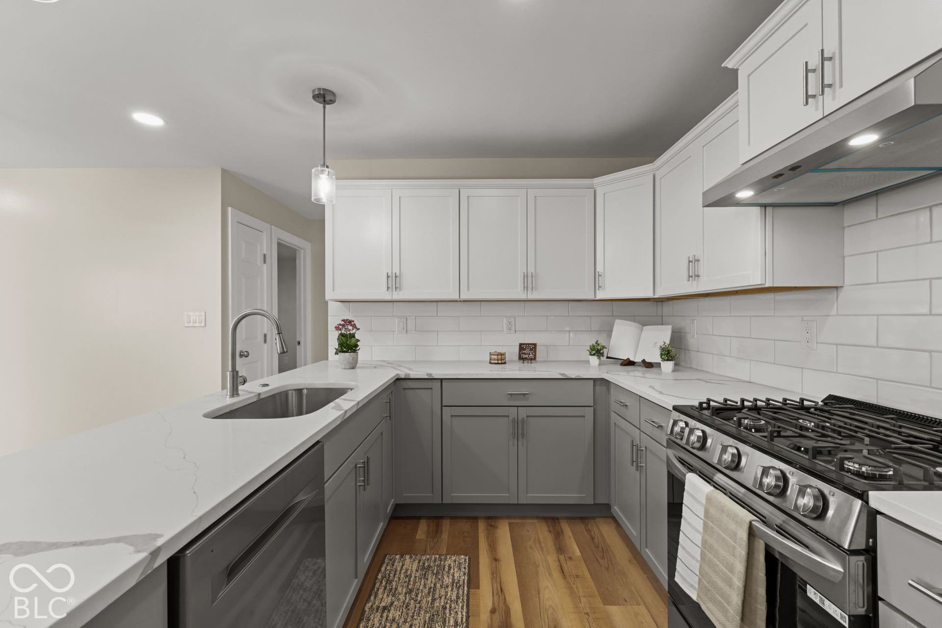 U-shaped kitchen featuring two-tone cabinetry, stainless steel appliances, a subway tile backsplash, and light-toned countertops