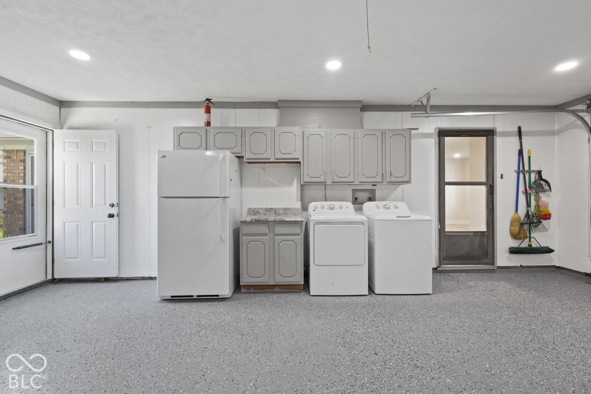 Finished garage with epoxy flooring, recessed lighting, wall-mounted cabinetry, and a utility sink with countertop