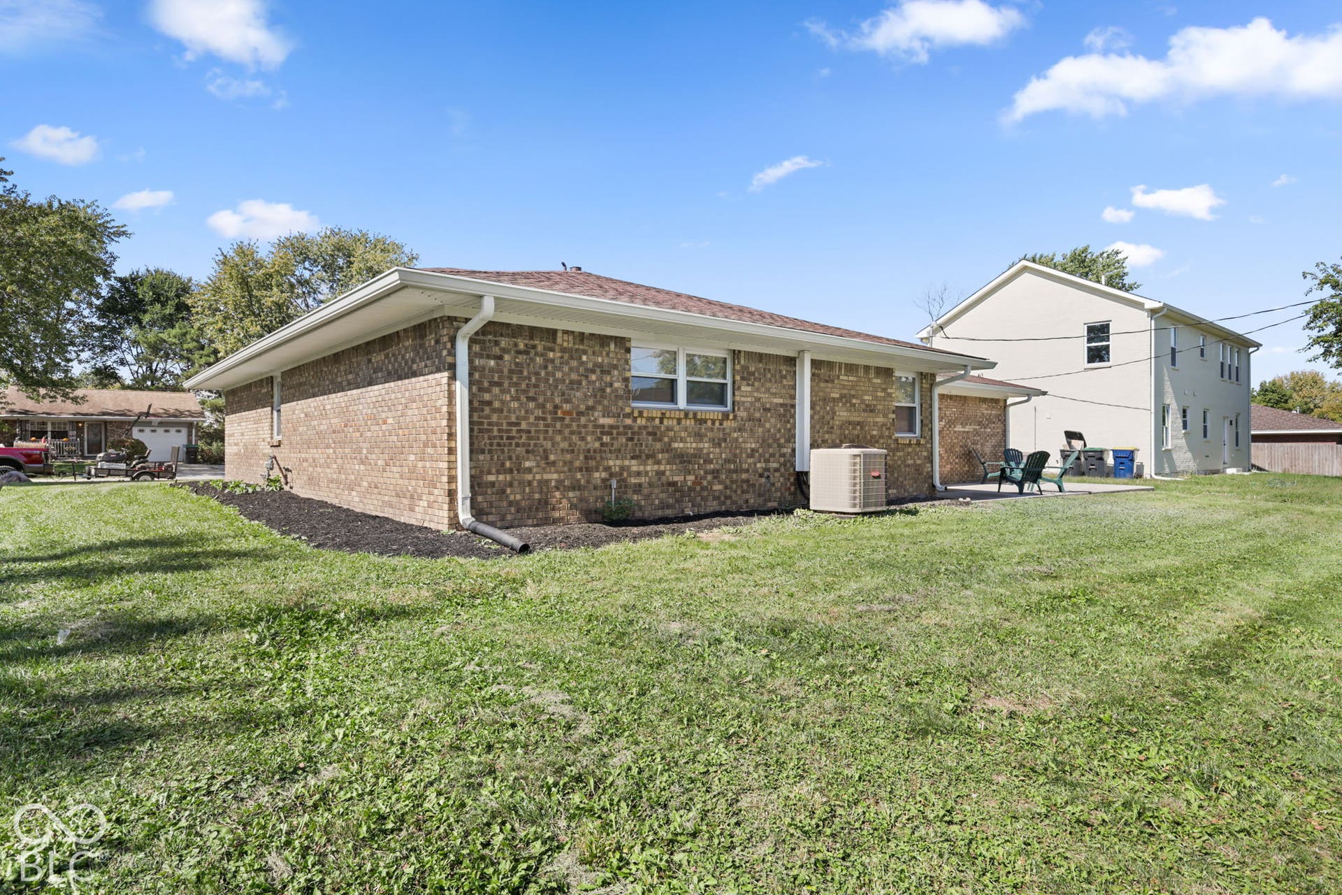 Brick exterior with white trim, brown shingle roof, and a concrete patio