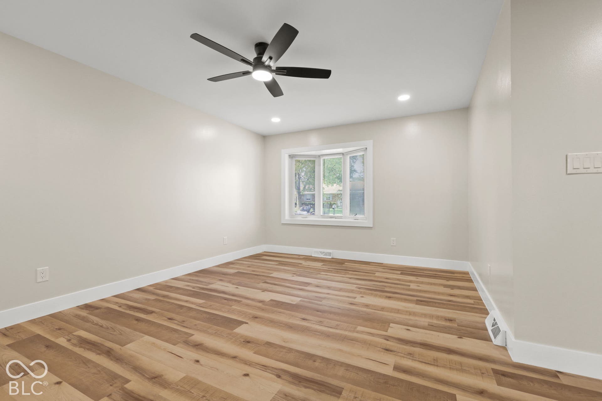 Wood-finish flooring, recessed lighting, ceiling fan, and a multi-pane window